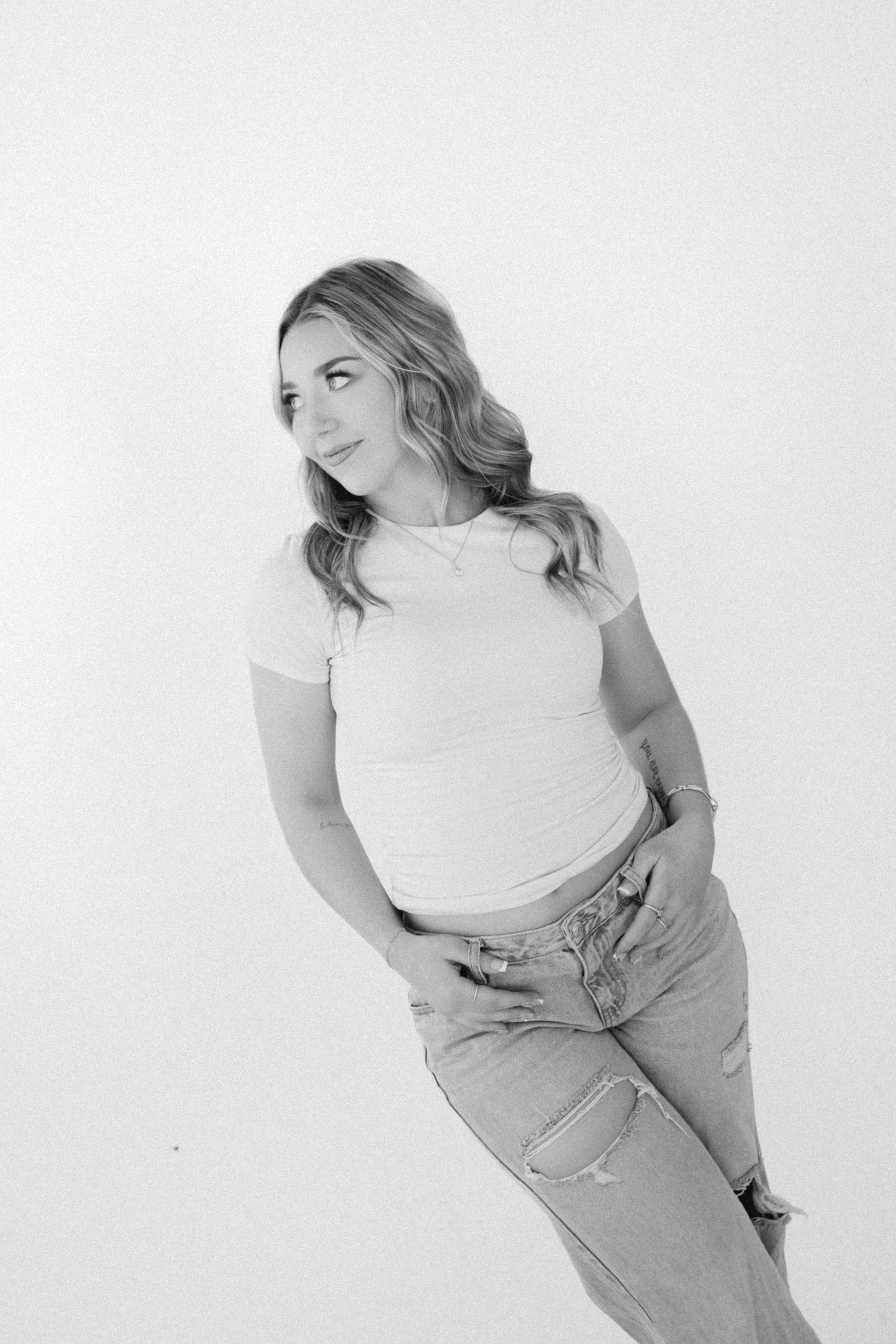 A series of black and white photos showing a person in a white top and jeans posing against a light background.