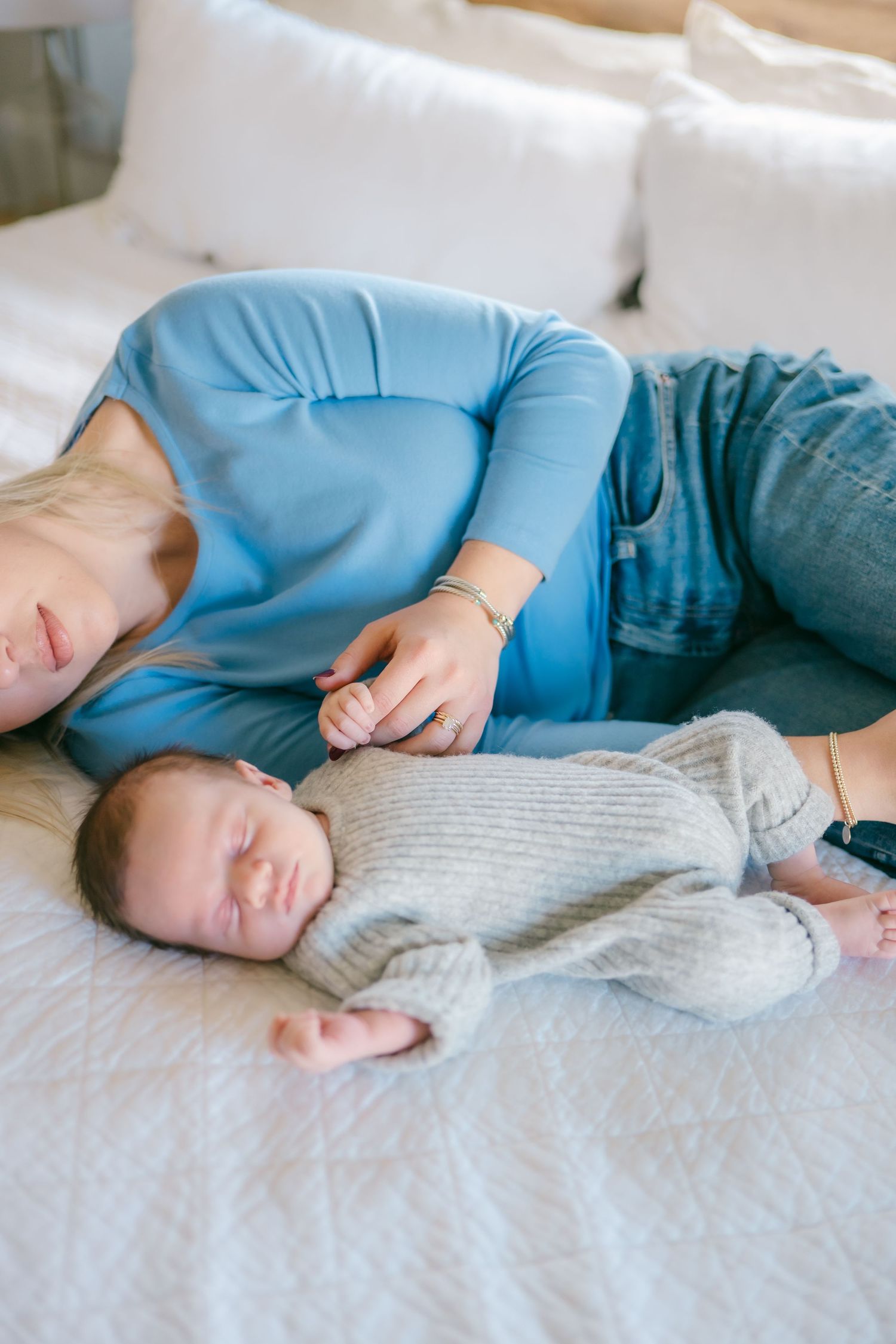 Couple resting together on white bed wearing casual blue clothing.