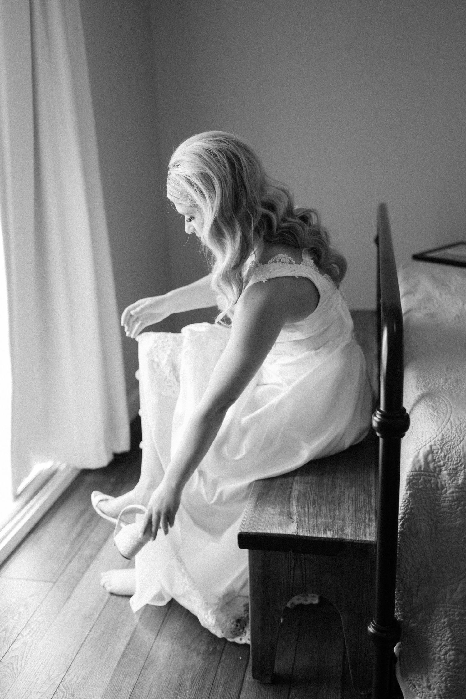 Black and white image of someone adjusting their shoes while sitting.