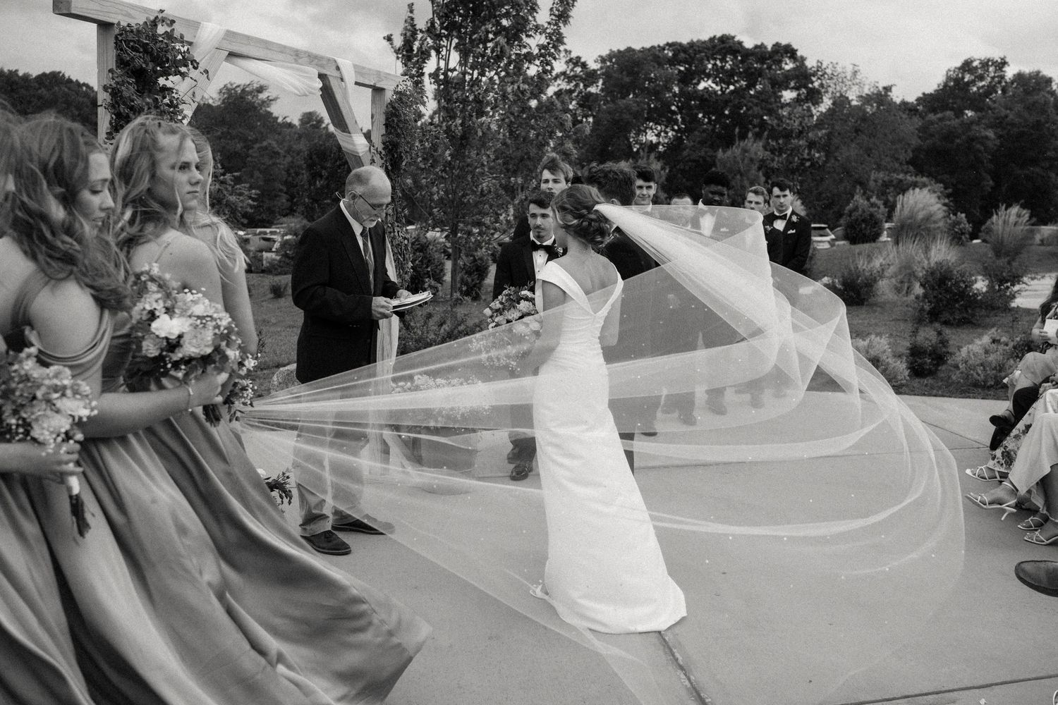 Wedding dress train flows dramatically during outdoor celebration.