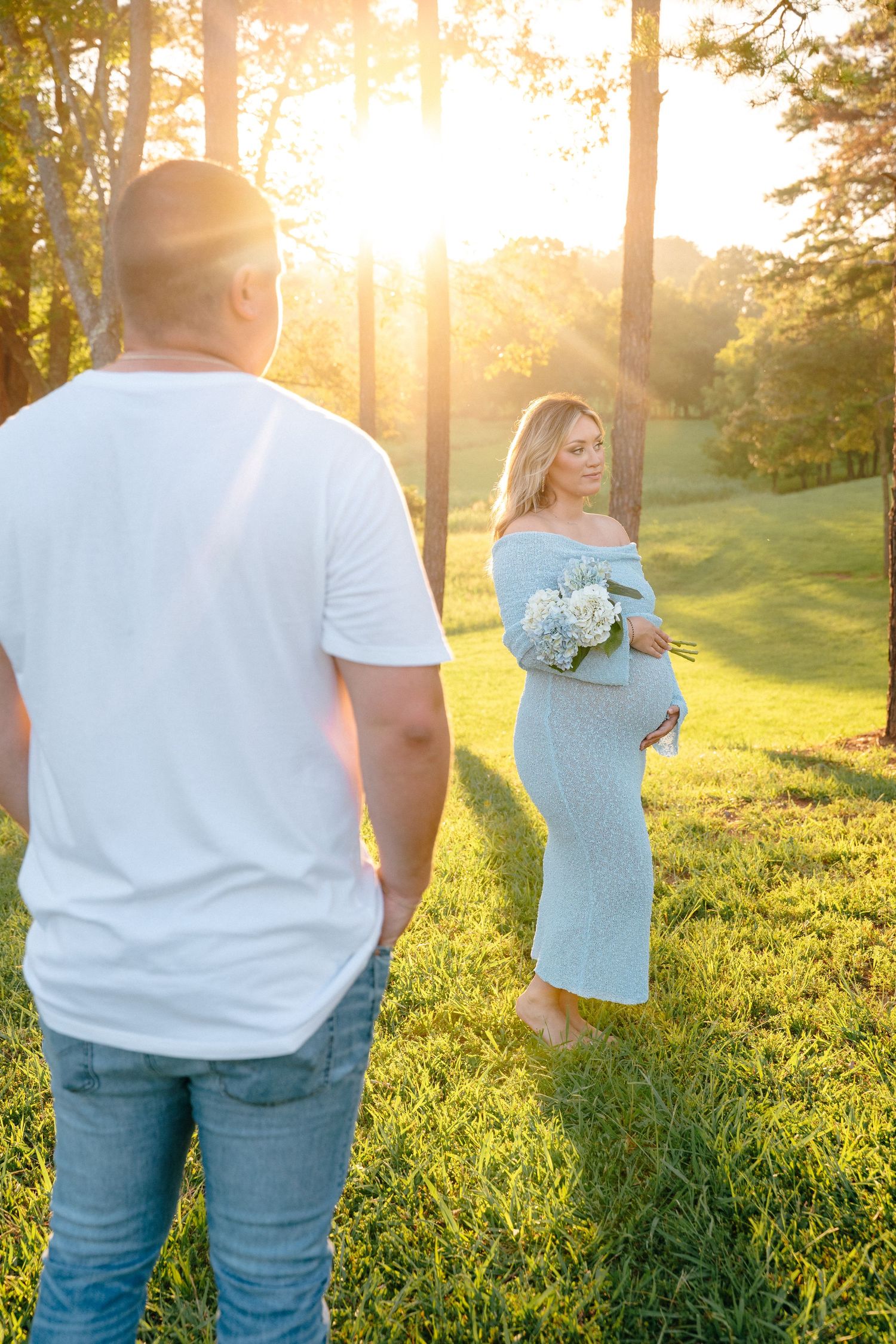 Sunset engagement photos in casual attire with hydrangea bouquet in grassy field.