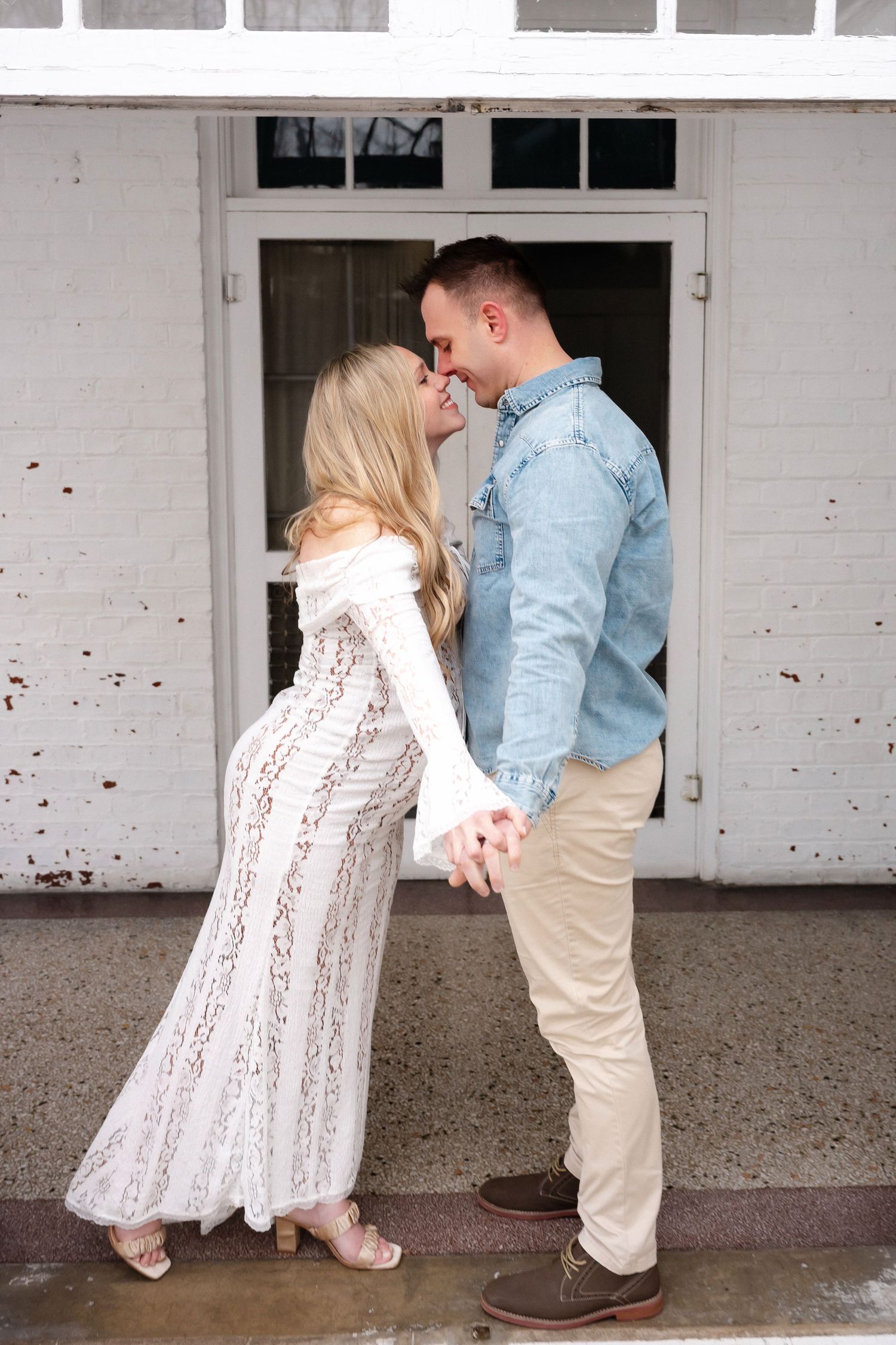 A couple dancing together in a white room with arched windows.