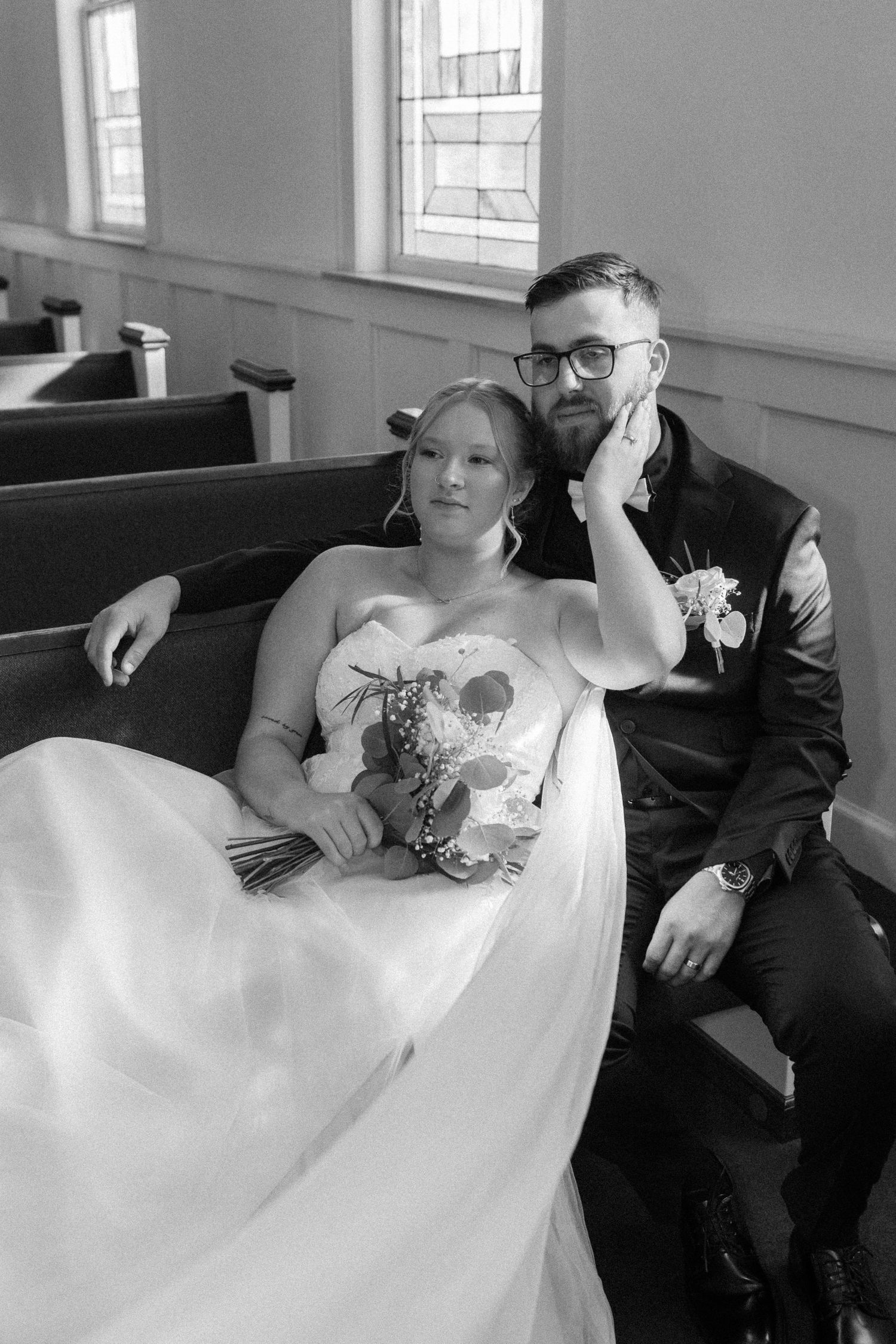 Black and white wedding photos in a church pew showing tender moments.