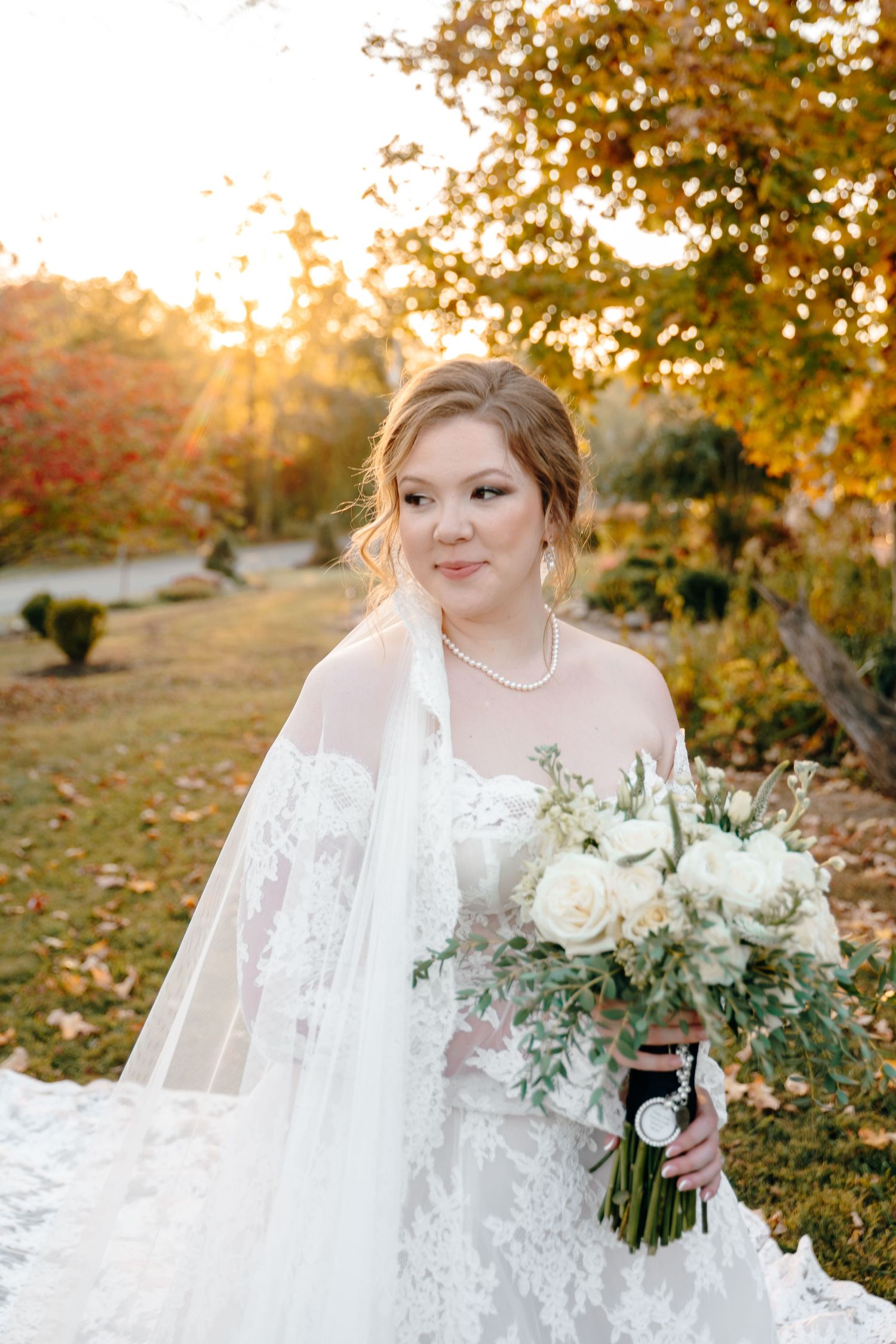 Beautiful autumn wedding portrait with white bouquet and lace dress details.