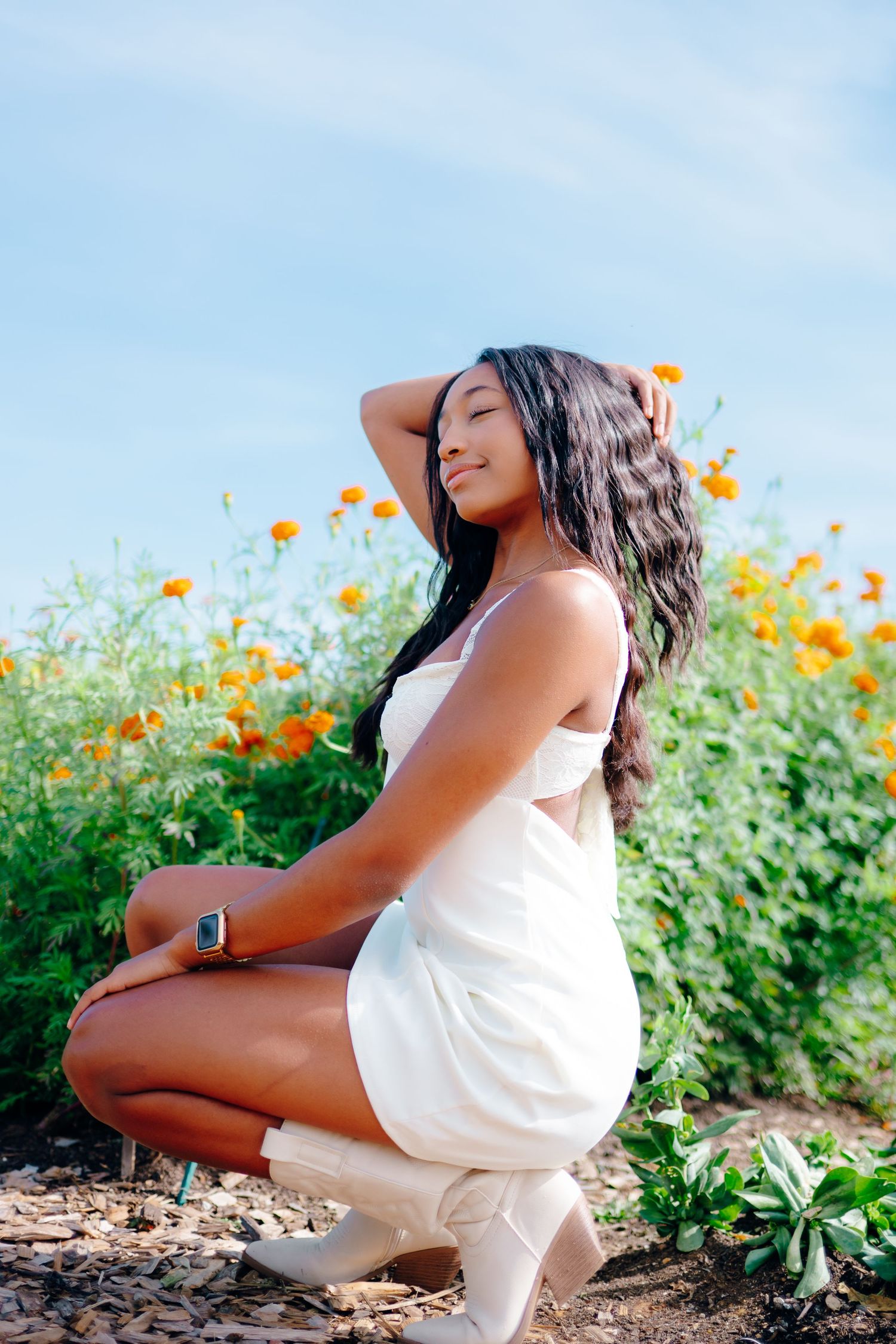 Outdoor photoshoot among vibrant orange wildflowers on a sunny summer day.