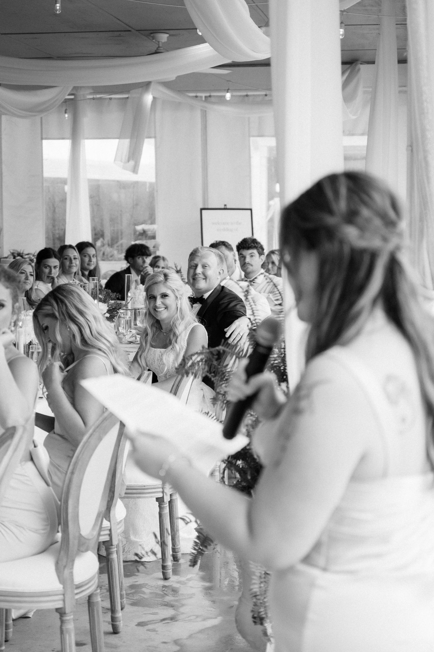Wedding reception party dancing in white-draped indoor venue.