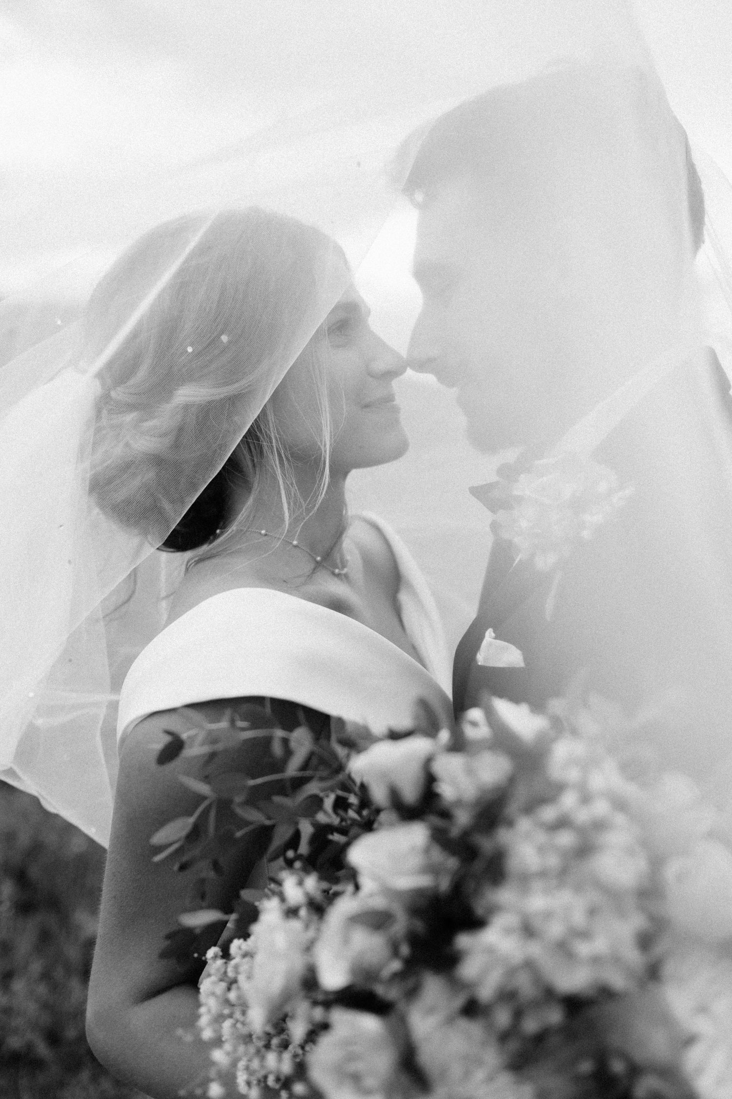Romantic black and white portrait through delicate bridal veil with flowers.