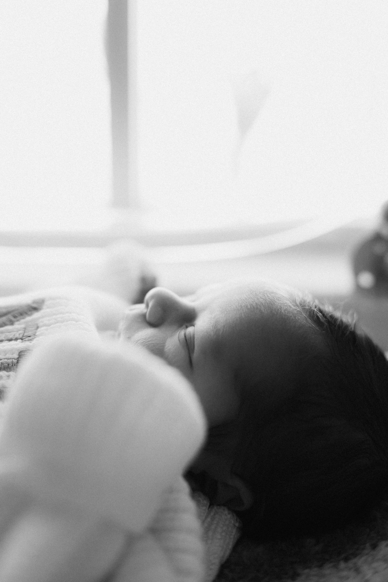 Soft focus black and white image of a sleeping baby in profile.