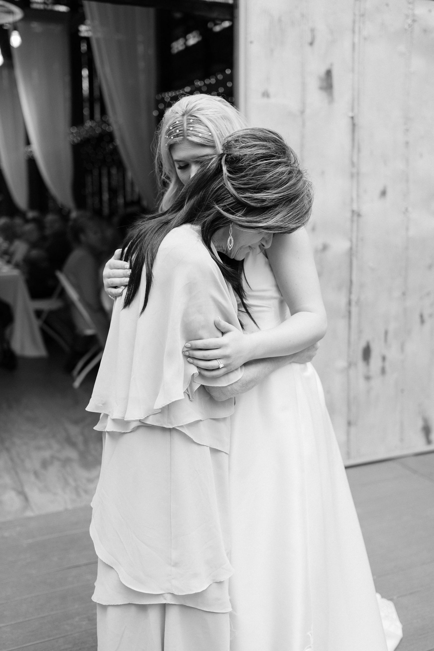 Intimate black and white portrait of two people embracing in formal attire.