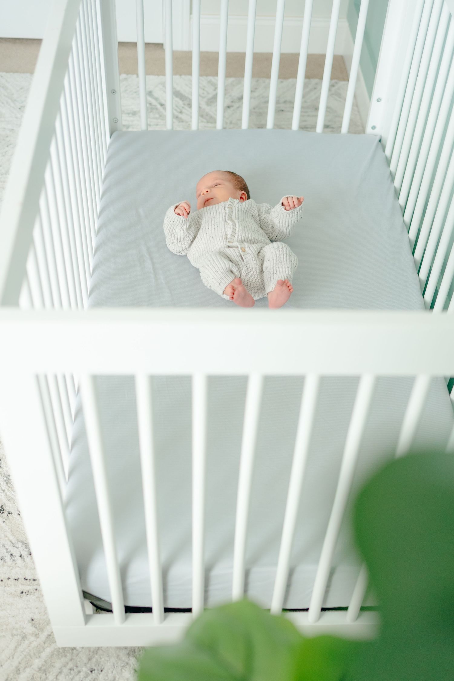 Baby sleeping peacefully in white wooden crib with soft bedding.