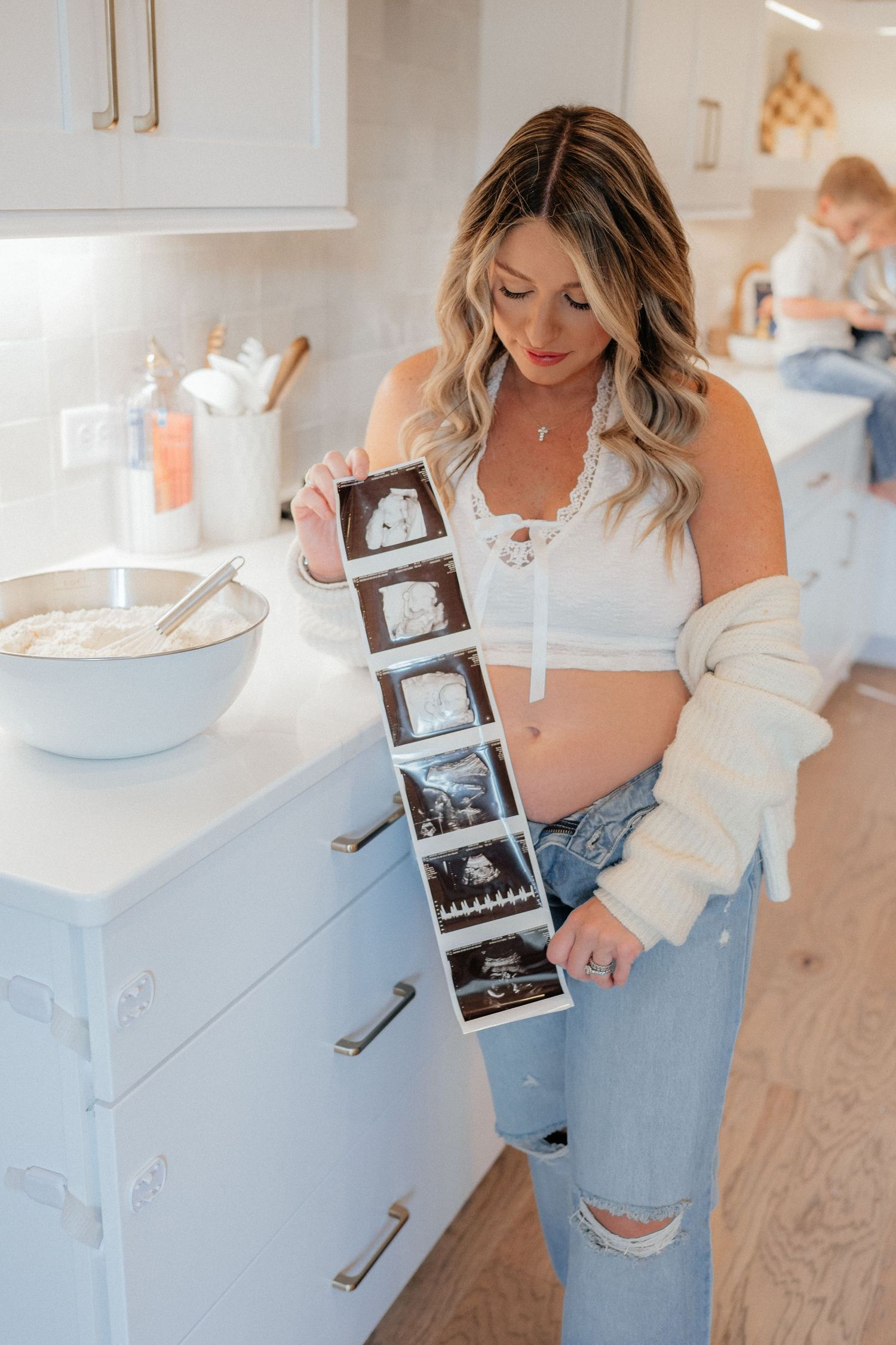 Pregnancy announcement photos showing ultrasound scans in a bright modern kitchen setting.
