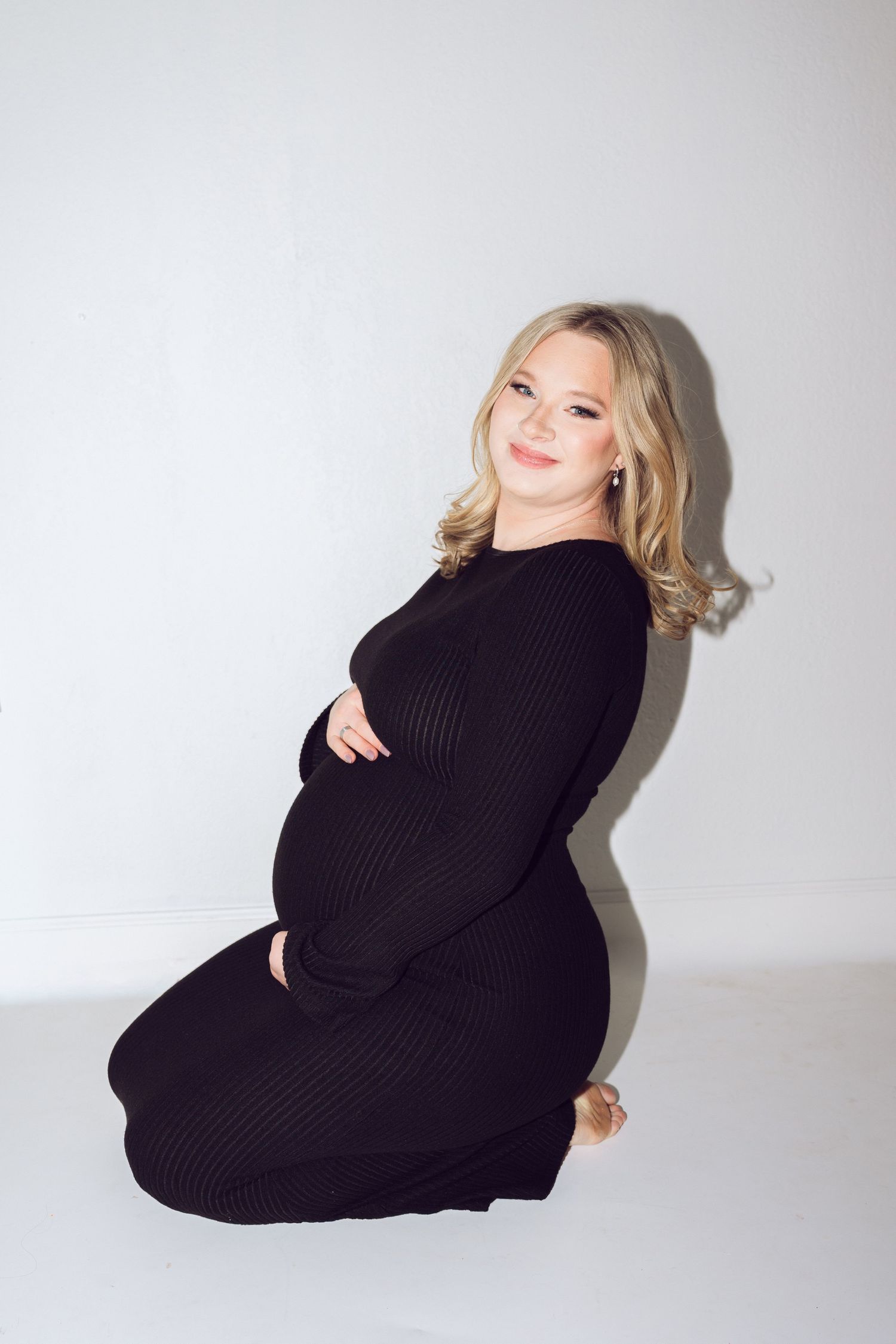 A person wearing a black sweater poses playfully on a white background in a series of artistic studio shots.