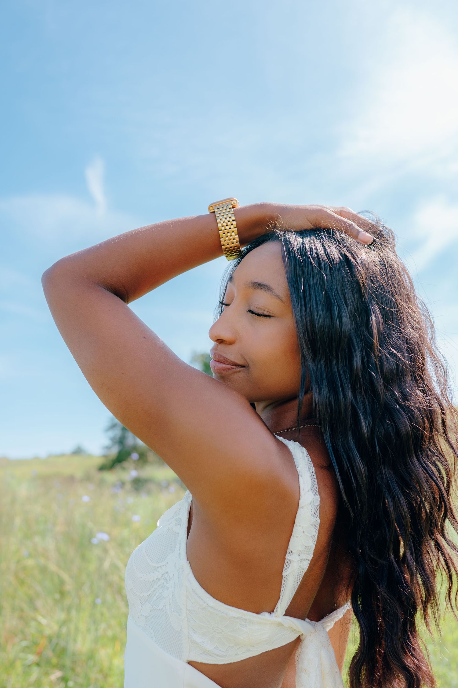 Sun-kissed portrait with long dark hair against bright blue sky.