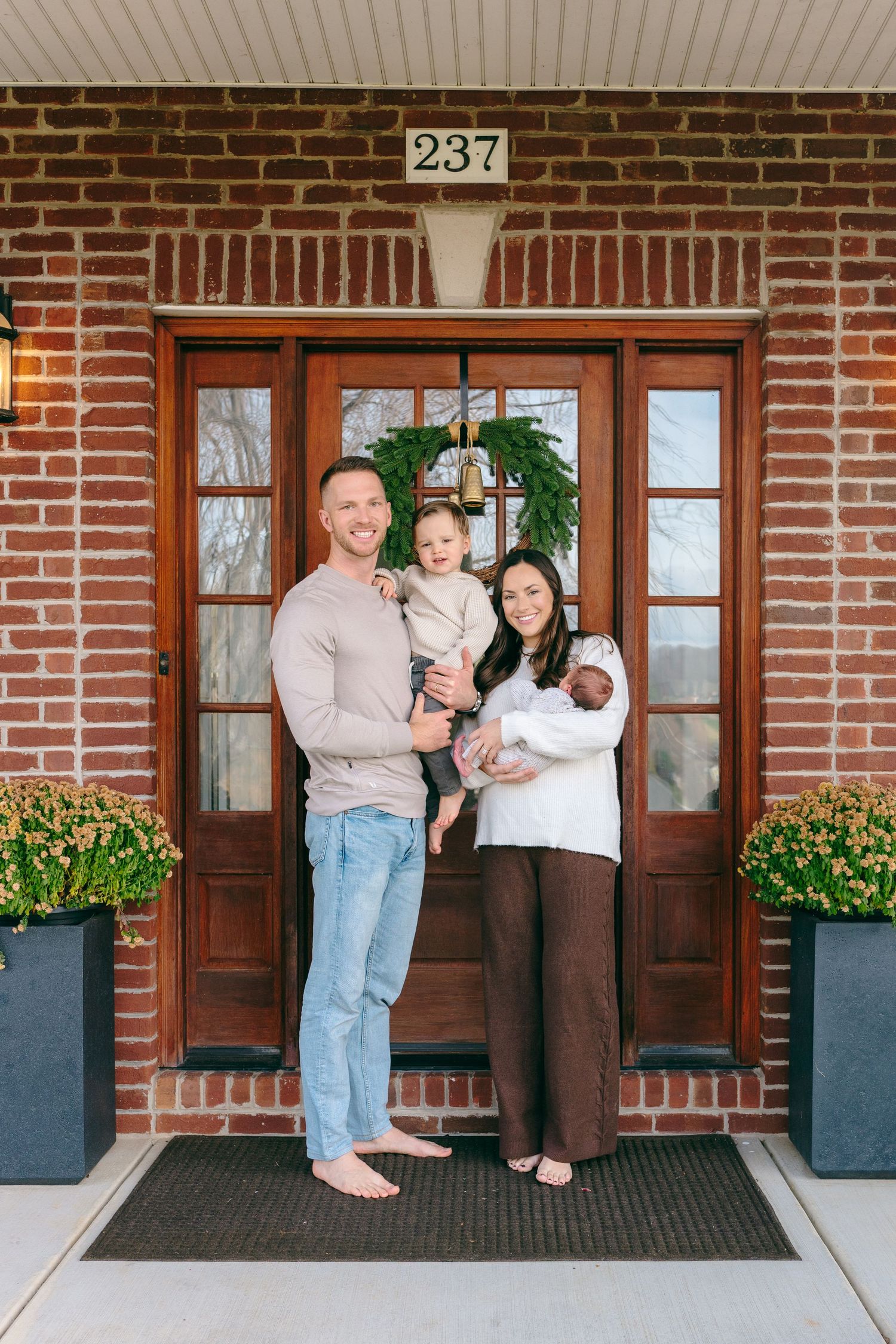 A family stands together on a brick porch with the house number 237 visible.