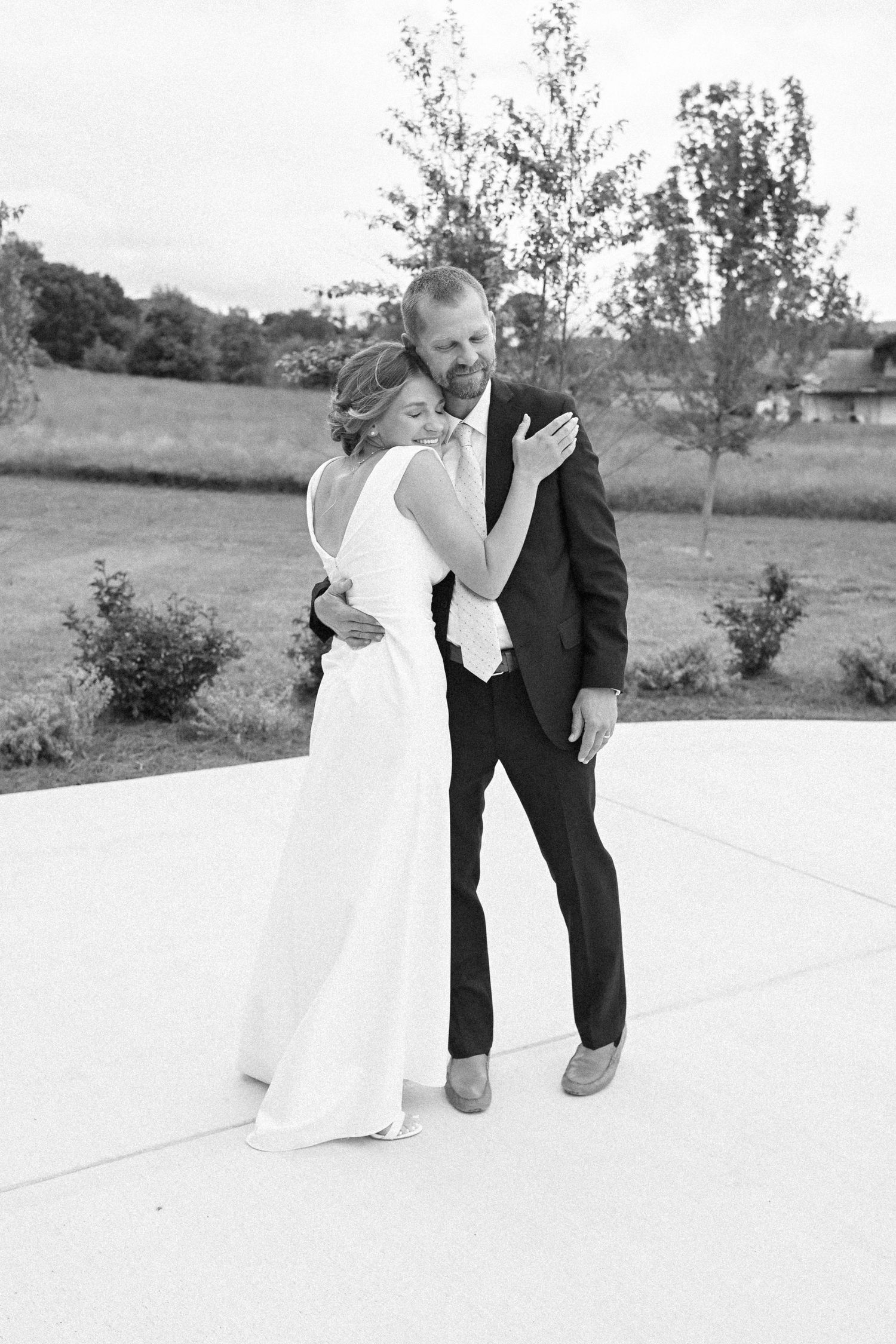 Black and white wedding photo of couple sharing intimate moment on outdoor patio.