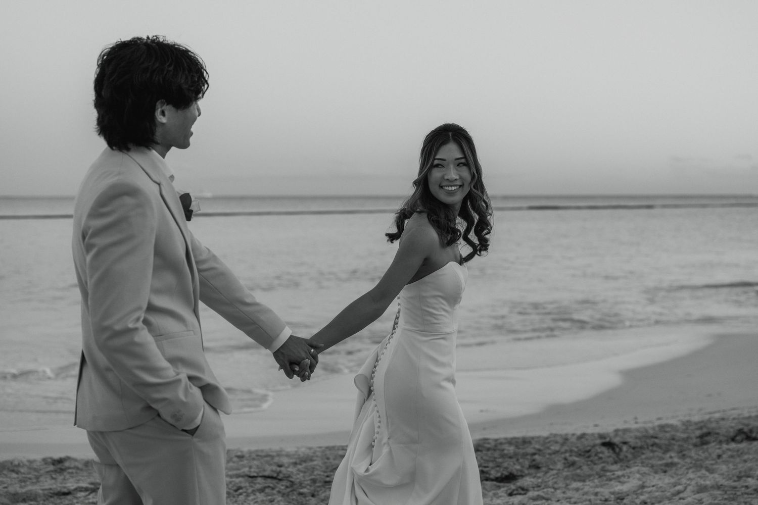 Happy bride and groom walking on Mexican beach in the Rivera Maya.
