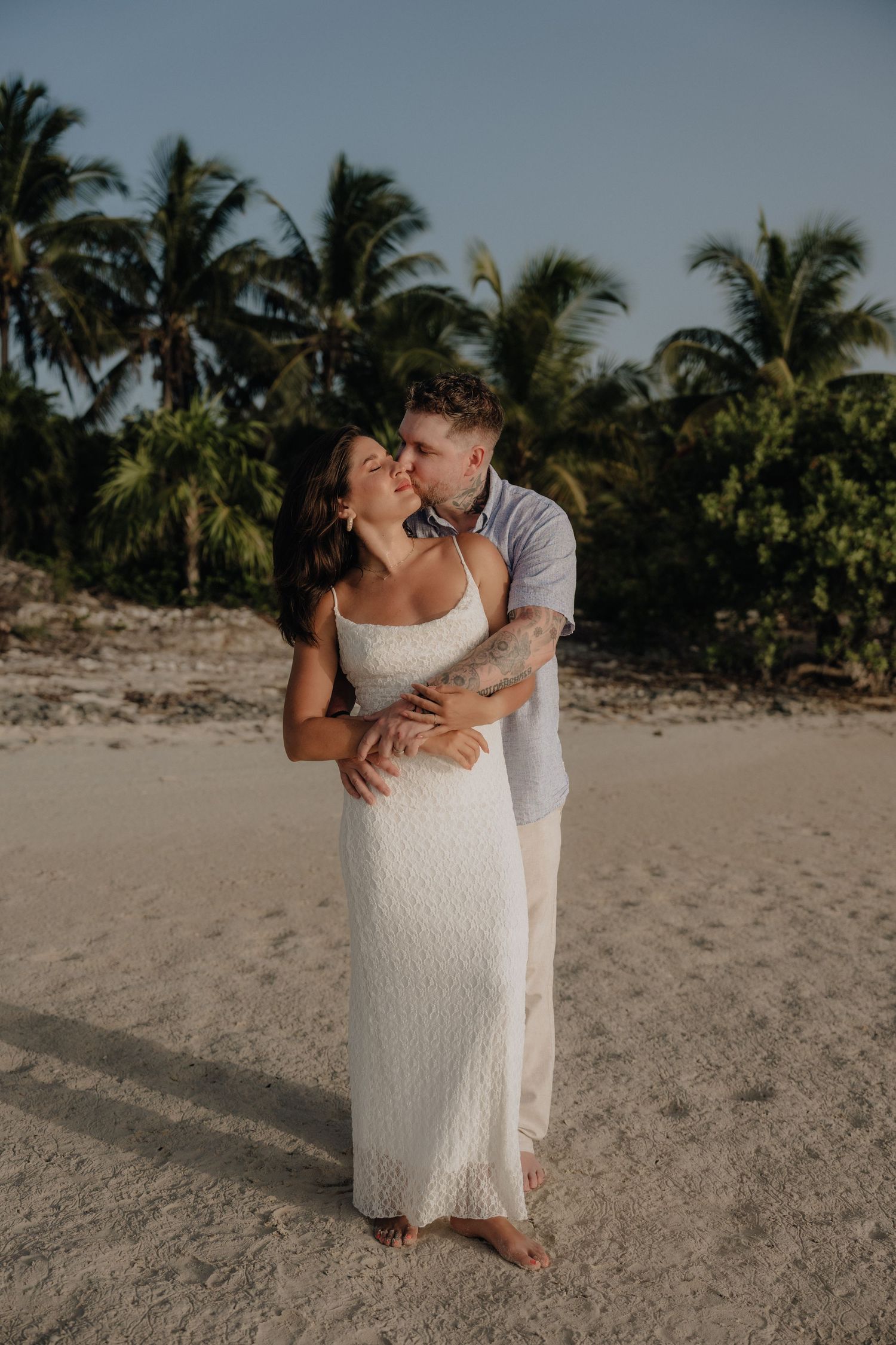 Bride and groom embracing on a sandy Mexican beach during an intimate and candid moment at golden hour, Cancún México