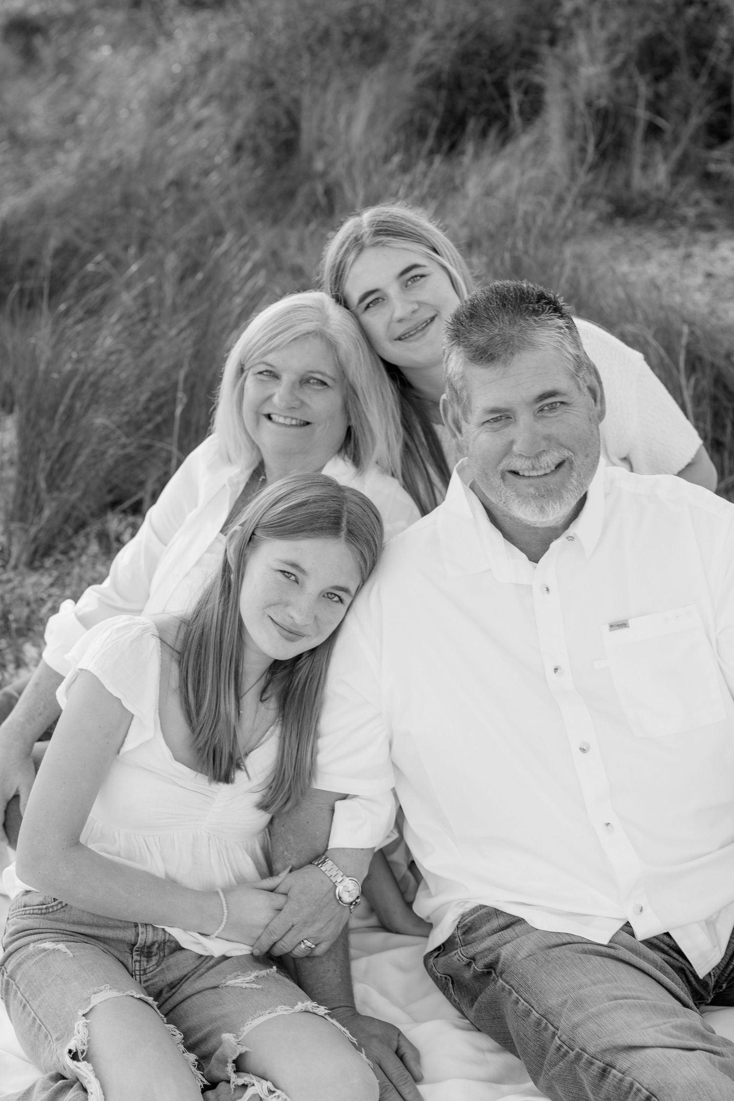 A family wearing white and denim poses together outdoors in a casual black and white photo series.