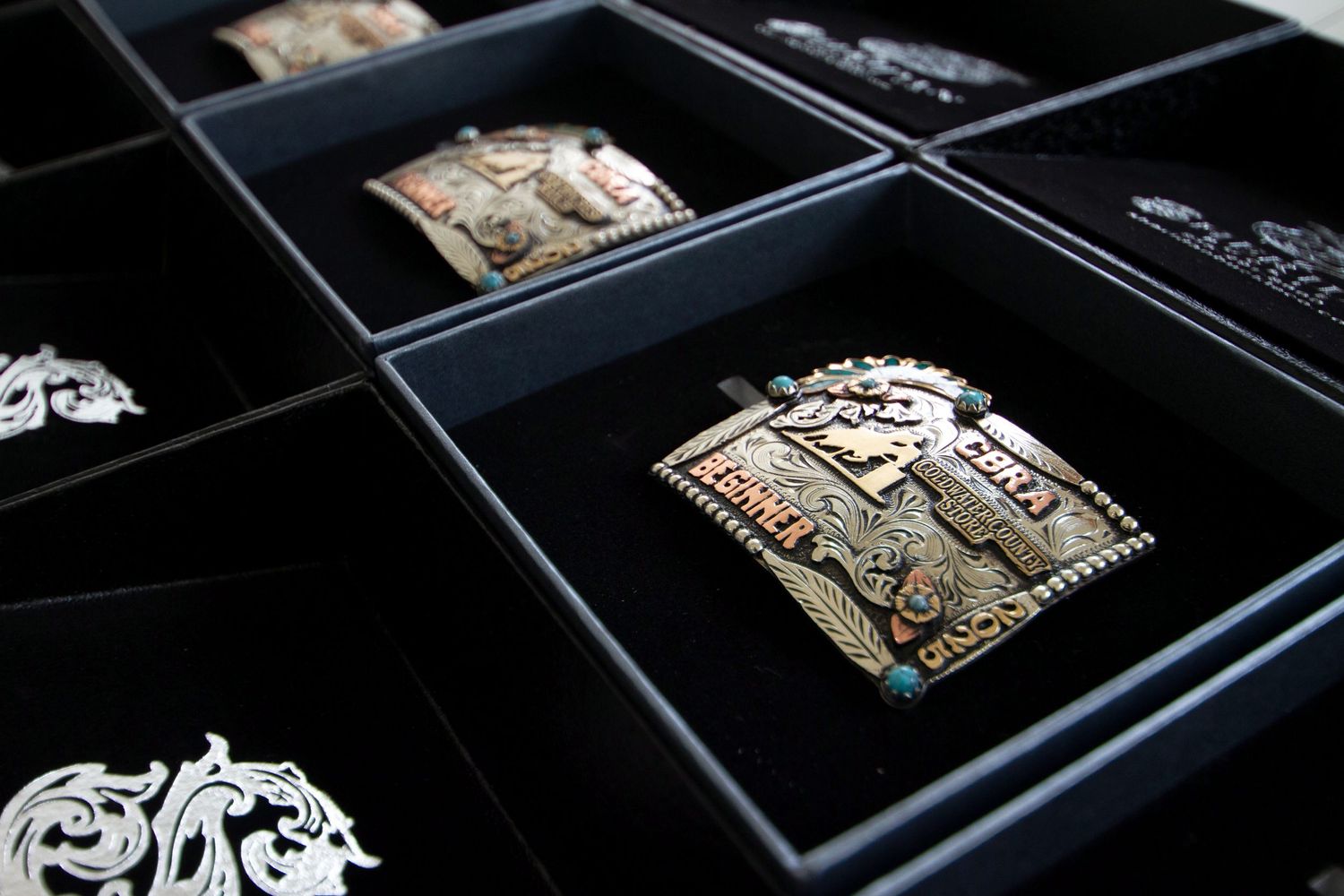 Artistic laser-cut tiles made of metal with intricate patterns displayed in black compartments of a storage case.