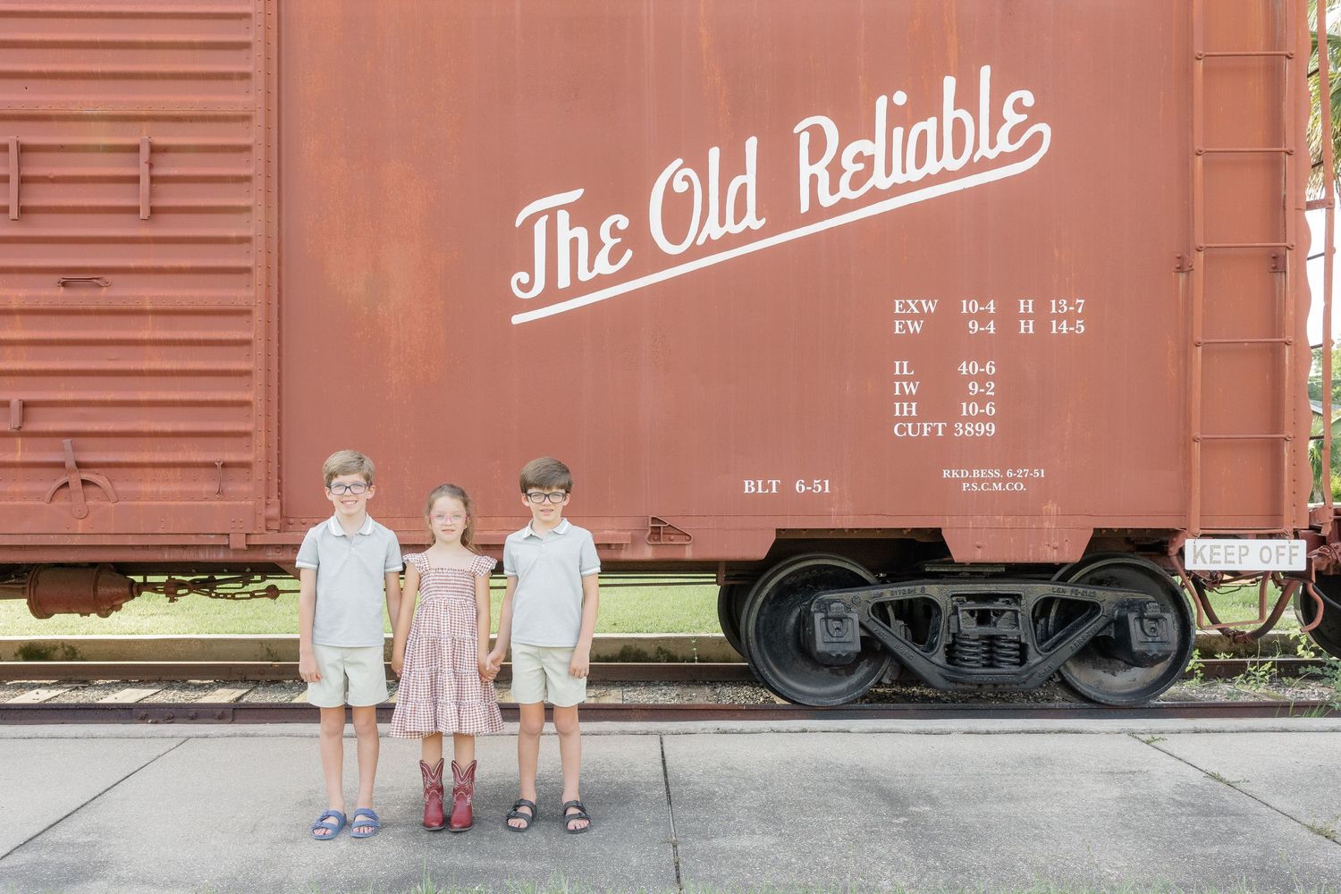 Three children standing in front of a vintage Louisville & Nashville The Old Reliable railroad boxcar.