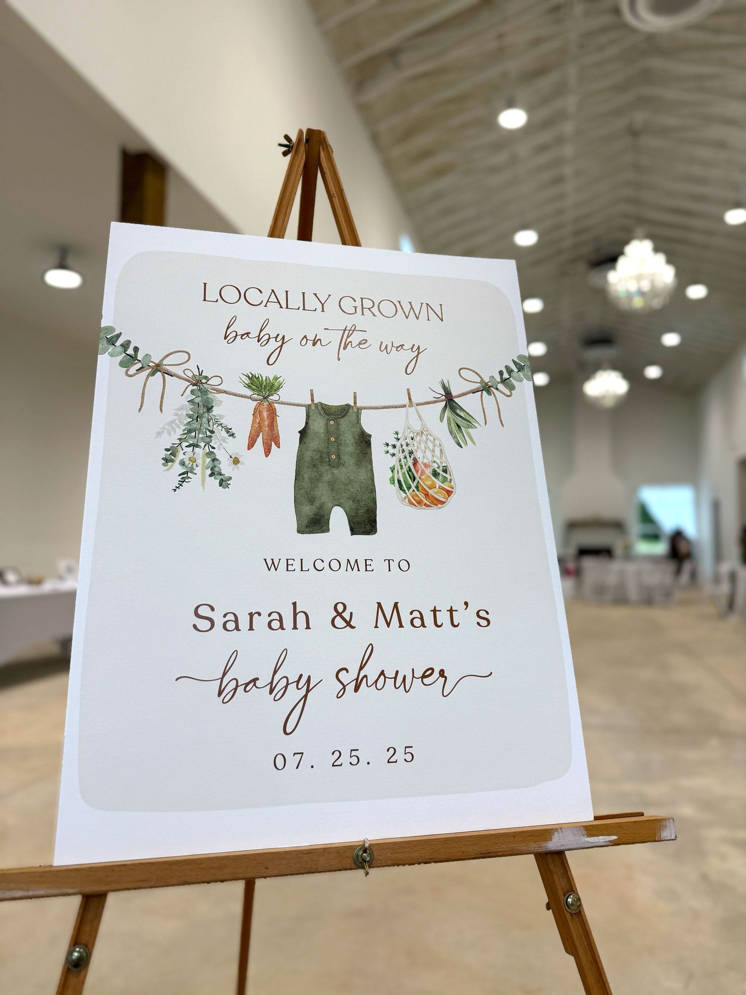 Baby shower welcome signs with clothes line illustration displayed on easels.