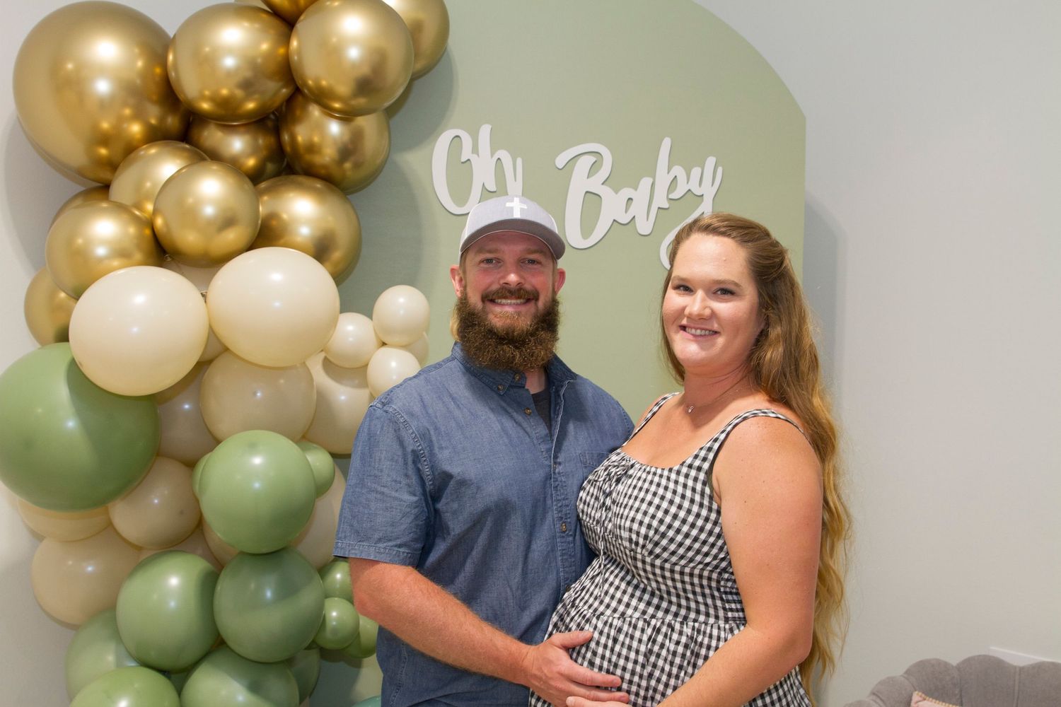Party decorations featuring gold and sage green balloons arranged in an elegant arch formation.
