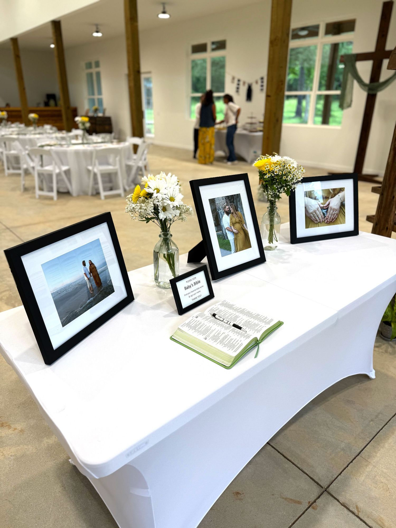 A white-clothed table displaying framed black and white photographs with small floral arrangements.