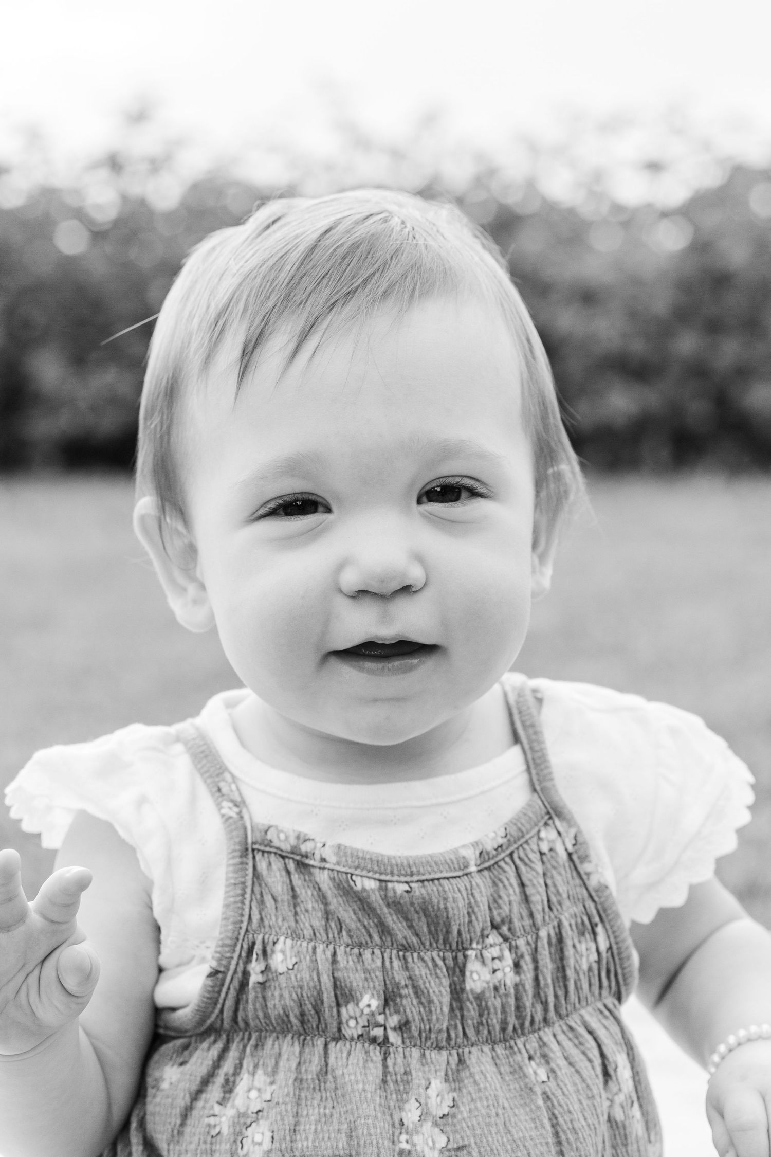A baby in a floral dress with angel wings smiles sweetly in a black and white photo collage.
