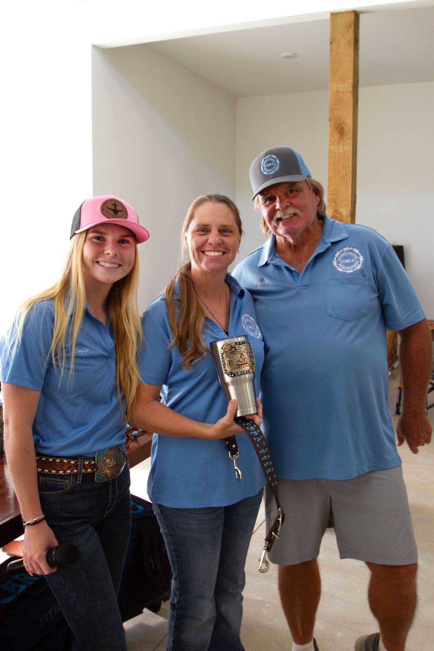 Group of people wearing matching blue polo shirts pose together in a white room for a photo.