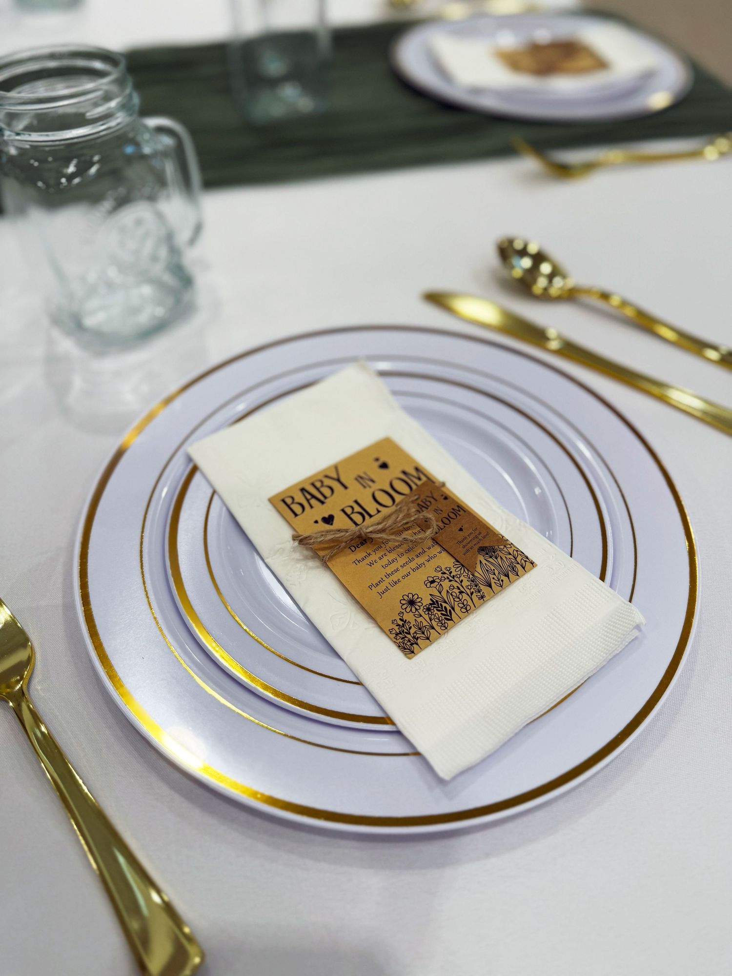 White and gold rimmed dinner plates with decorative cards set on an elegant table setting.