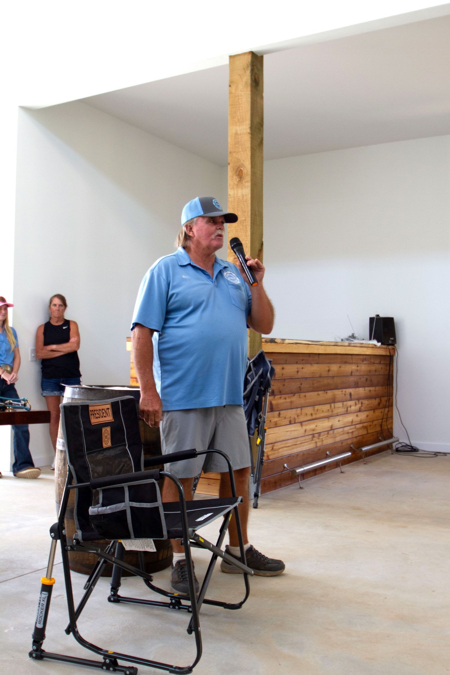 Installing wood paneling on interior walls with support posts and a temporary seating setup in progress.