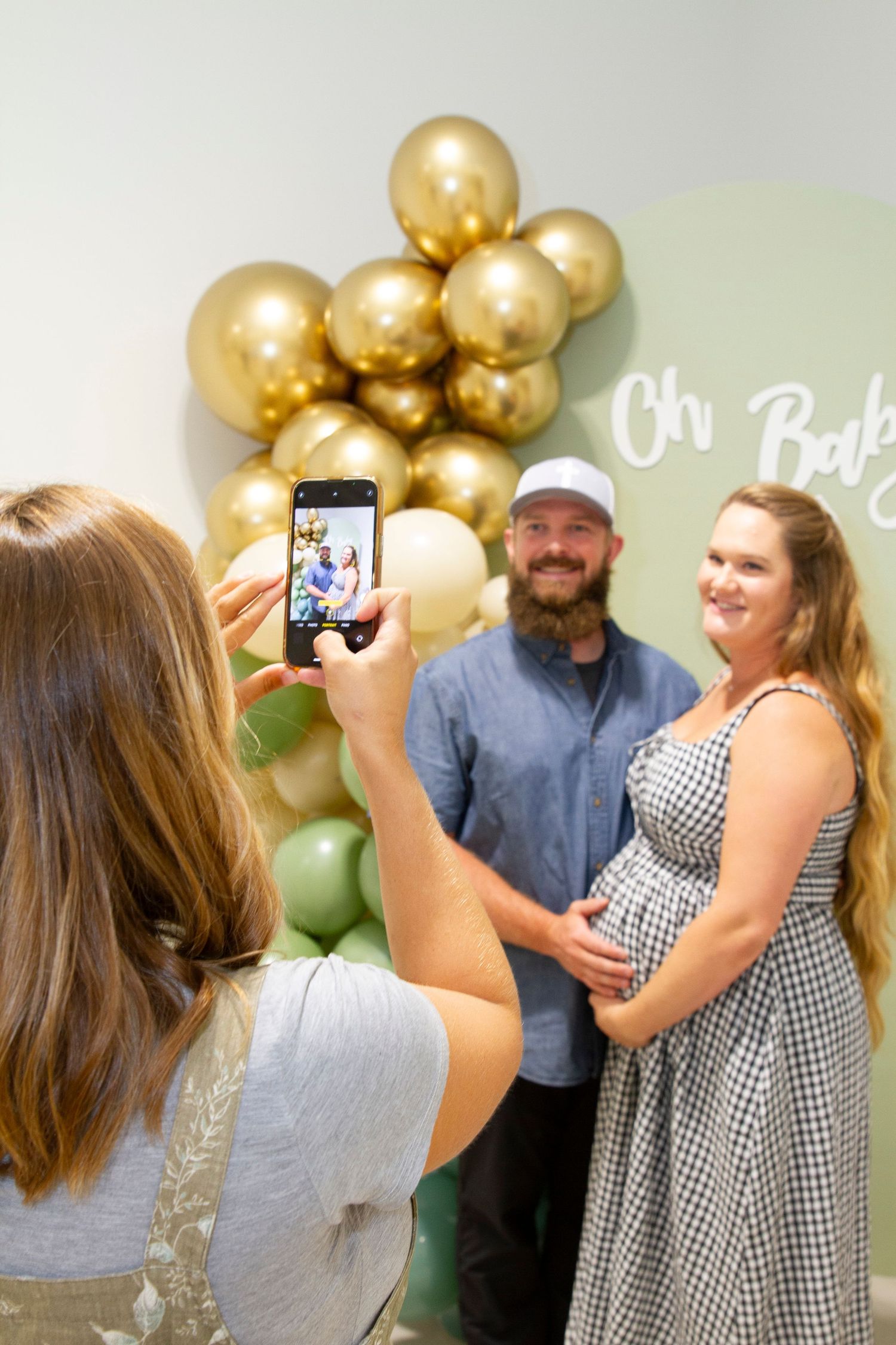 A baby shower celebration scene with gold and green balloon decorations.