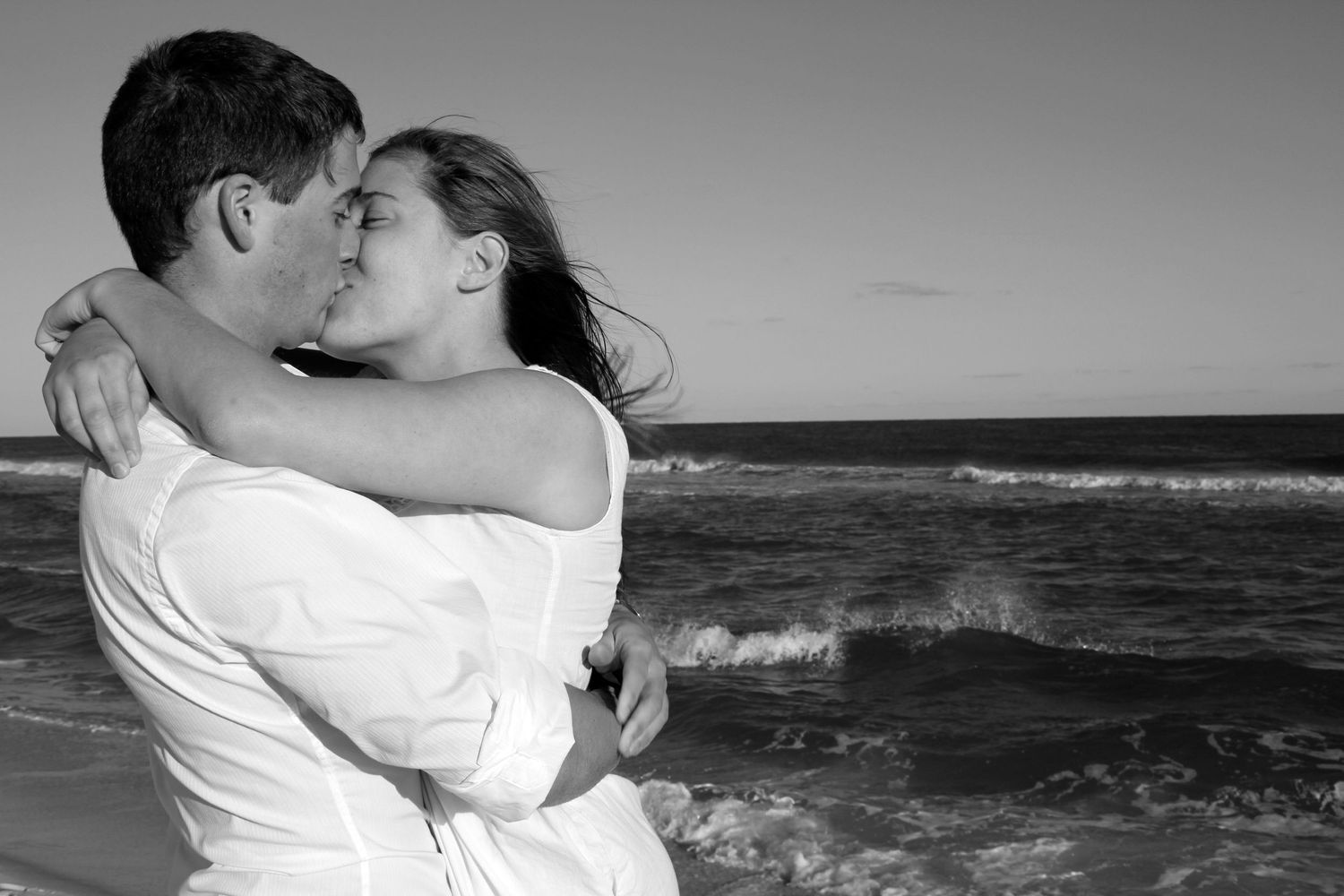 A romantic black and white series of beach embrace photos showing passionate couples against an ocean backdrop.