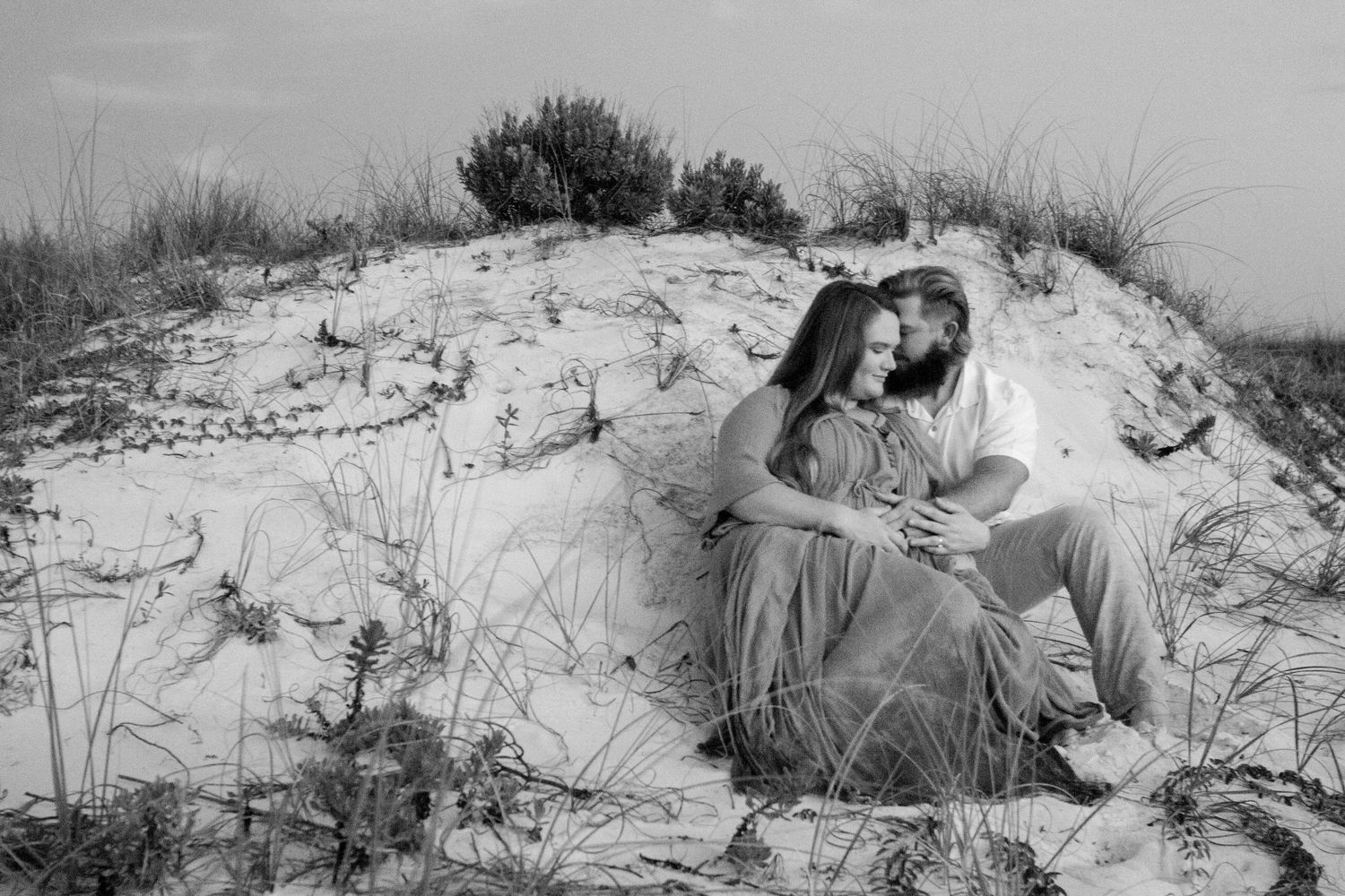 A collection of vintage black and white photographs showing people resting and relaxing on sandy dunes at the beach.