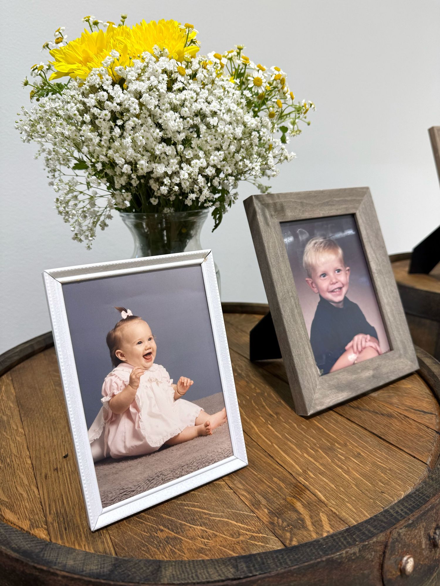 Yellow flowers and baby's breath arrangements displayed next to picture frames on a wooden surface.