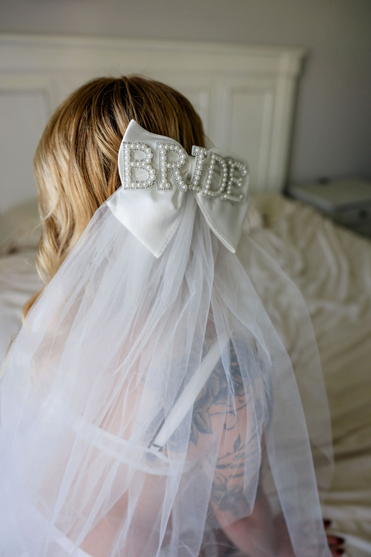 A delicate white tulle bridal veil with a sparkly bow detail is displayed on a light background.