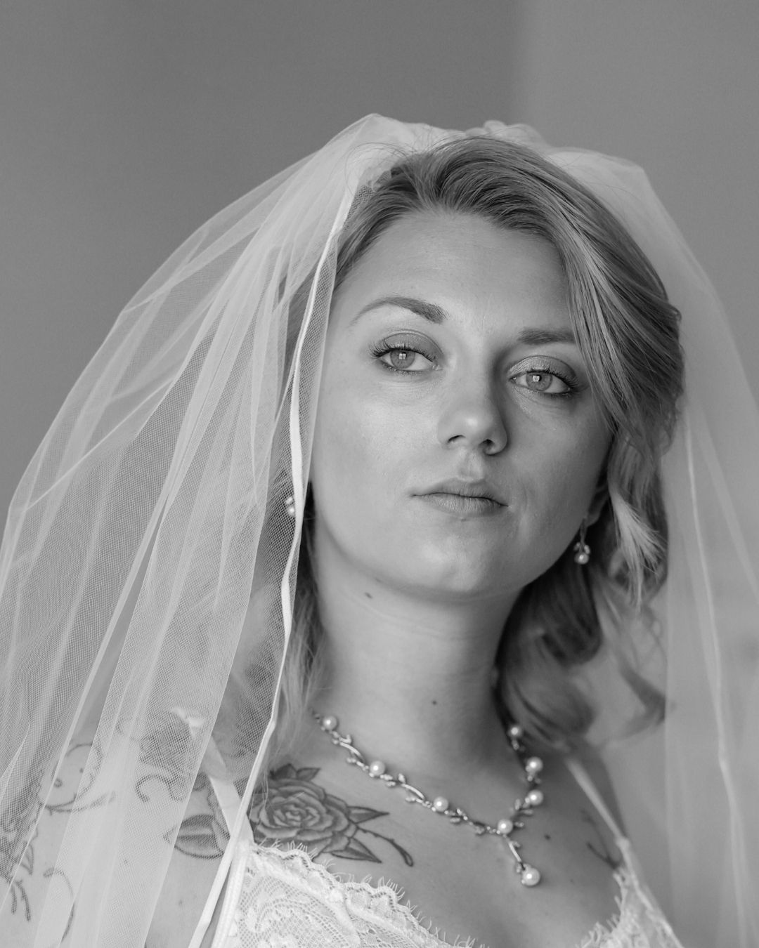 A series of black and white portraits showing a bride in a white veil and necklace with varying expressions.