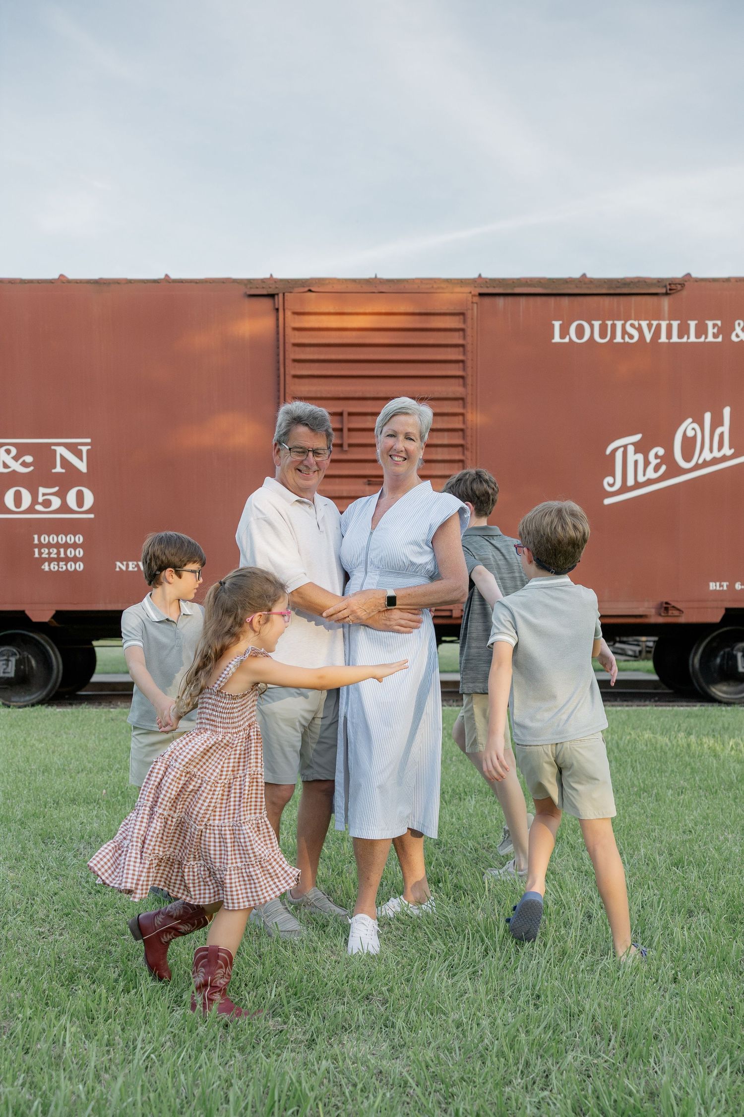 Family portrait with grandparents and four children playing outdoors near a vintage Louisville railroad boxcar.