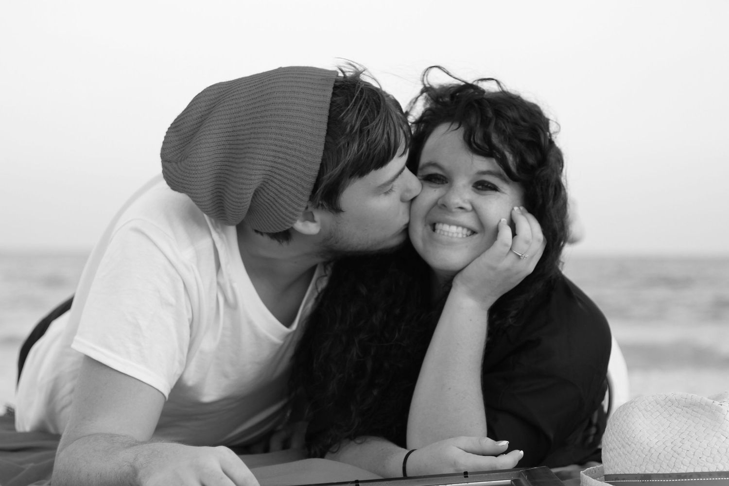 Four black and white romantic photos showing couple embracing at the beach.