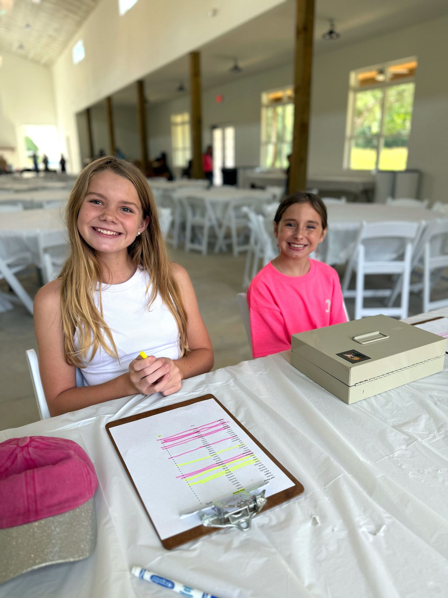 Young students working on worksheets at white tables in bright indoor space.