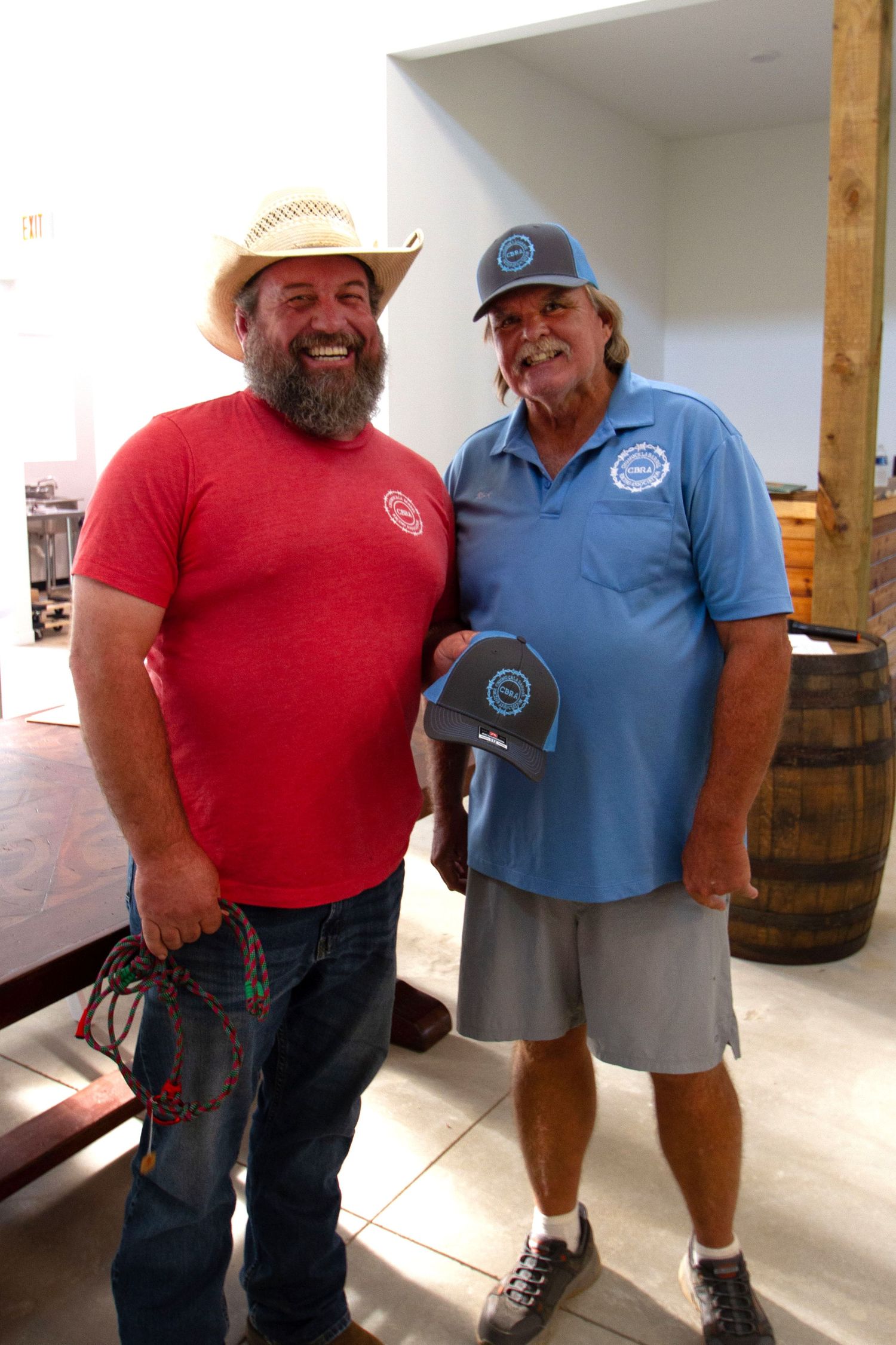 Two team members pose next to wooden barrel in casual attire at warehouse venue.
