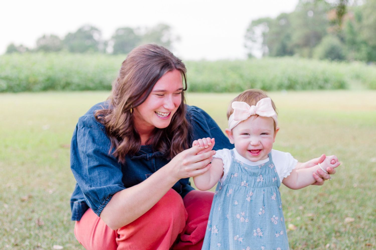 Family members share joyful moments together while playing outdoors in a grassy field on a sunny day.