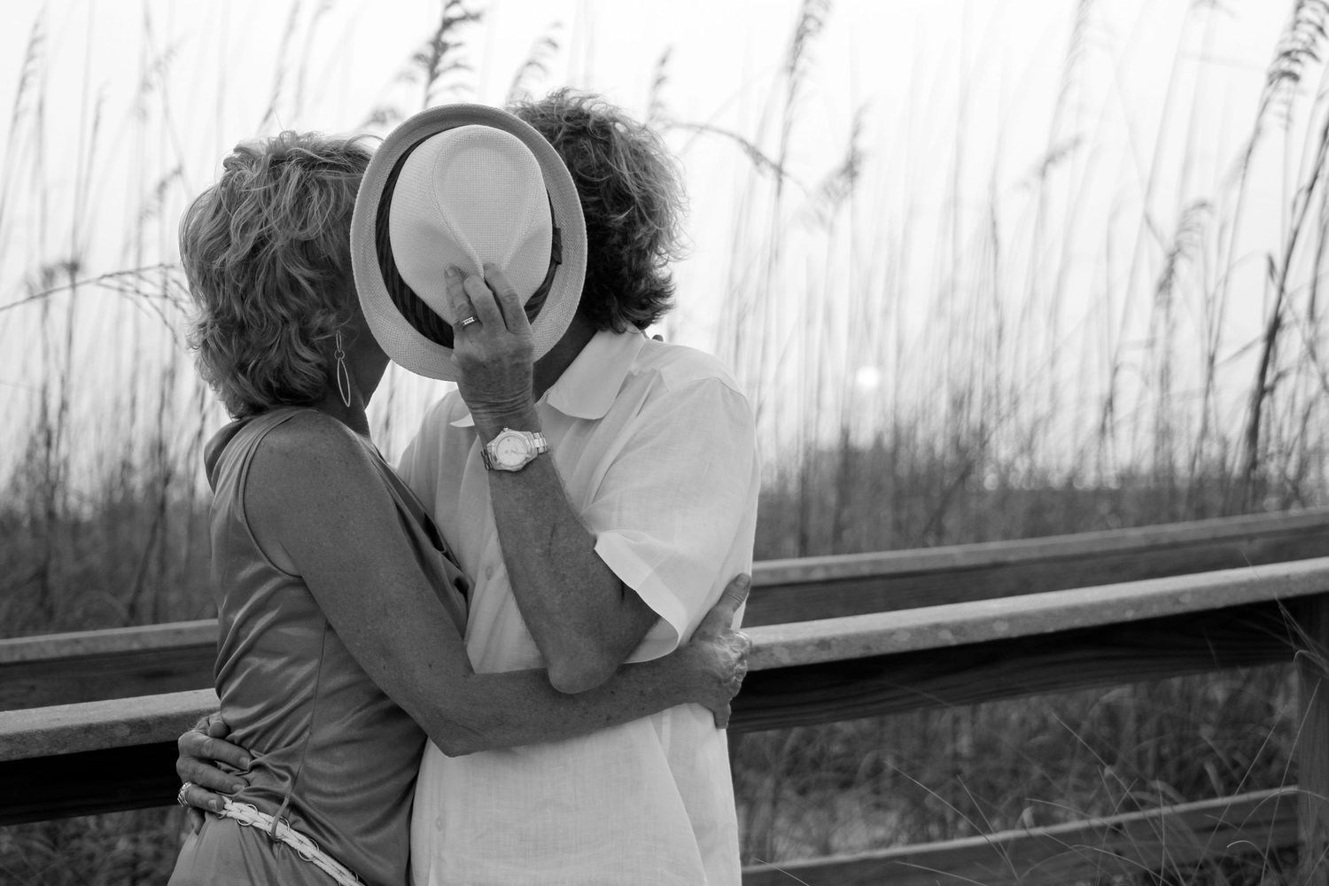 Black and white photo series of a couple enjoying an intimate moment by tall grass. Pensacola Beach. Wedding Anniversary shoot. Portraits.