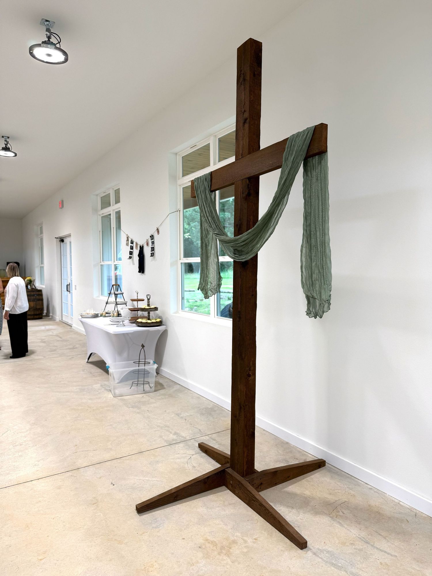 Wooden cross-shaped stands arranged in a bright white room with natural lighting and windows.