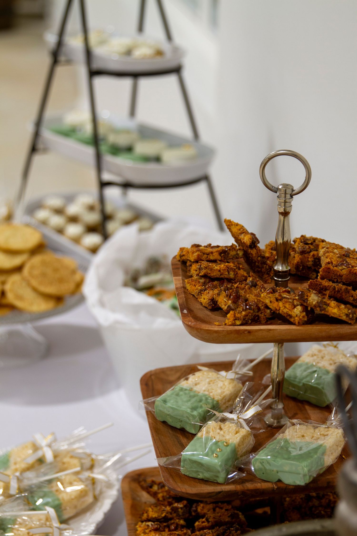 A dessert table display featuring green and brown pastries or treats arranged on tiered serving platters.
