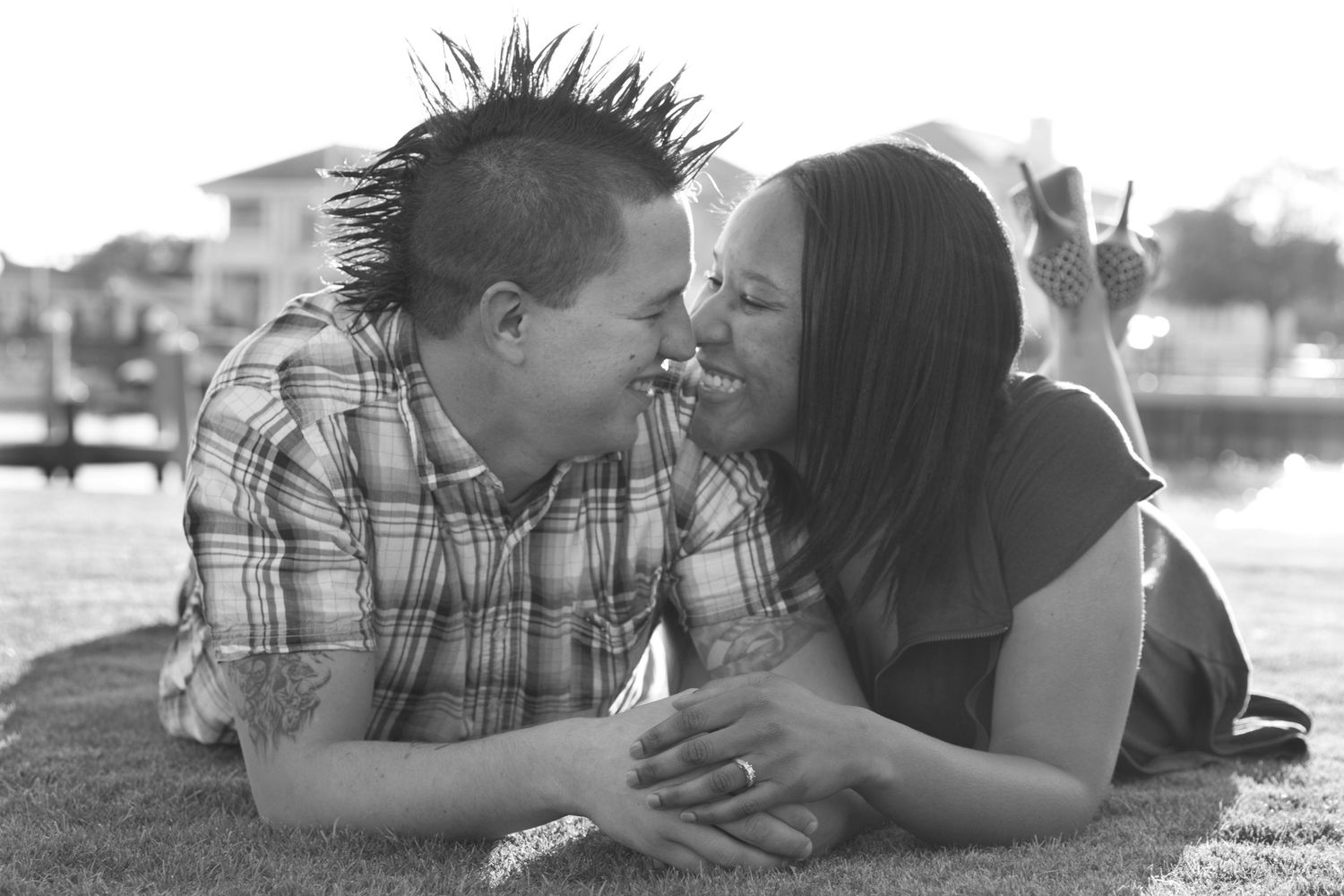 A loving couple lies in the grass together sharing an intimate moment in black and white photography.