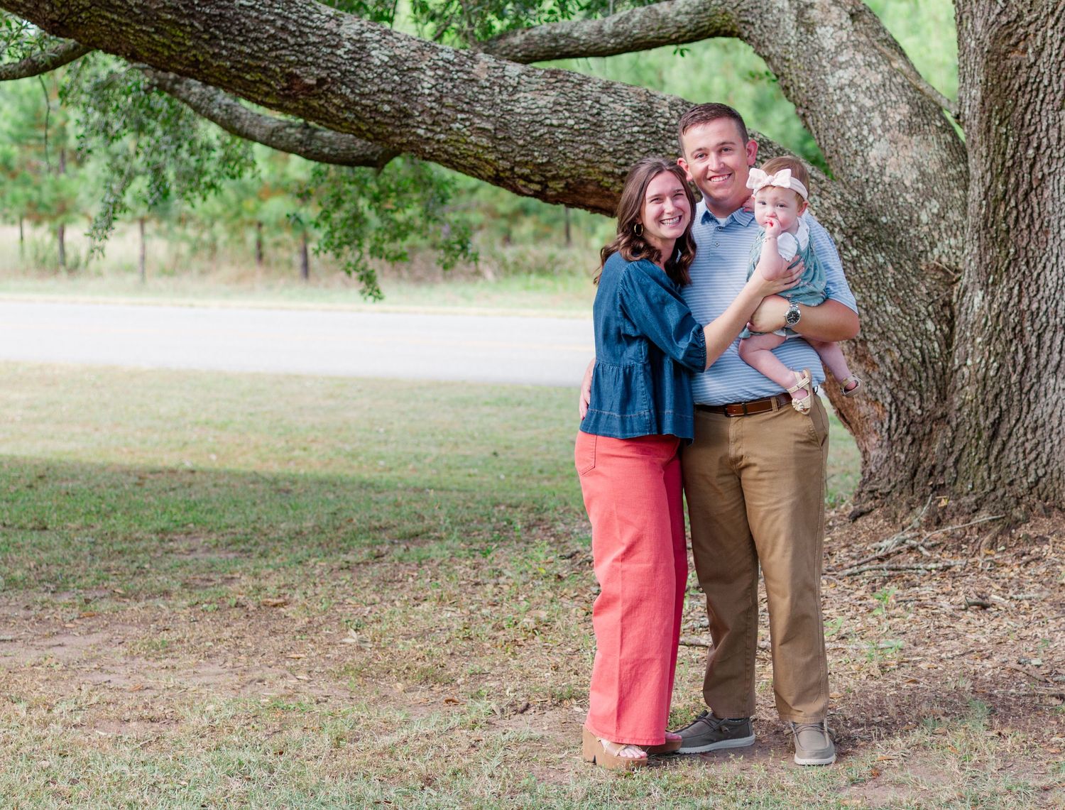 A couple poses together under large oak trees in an outdoor park setting during a photo session.