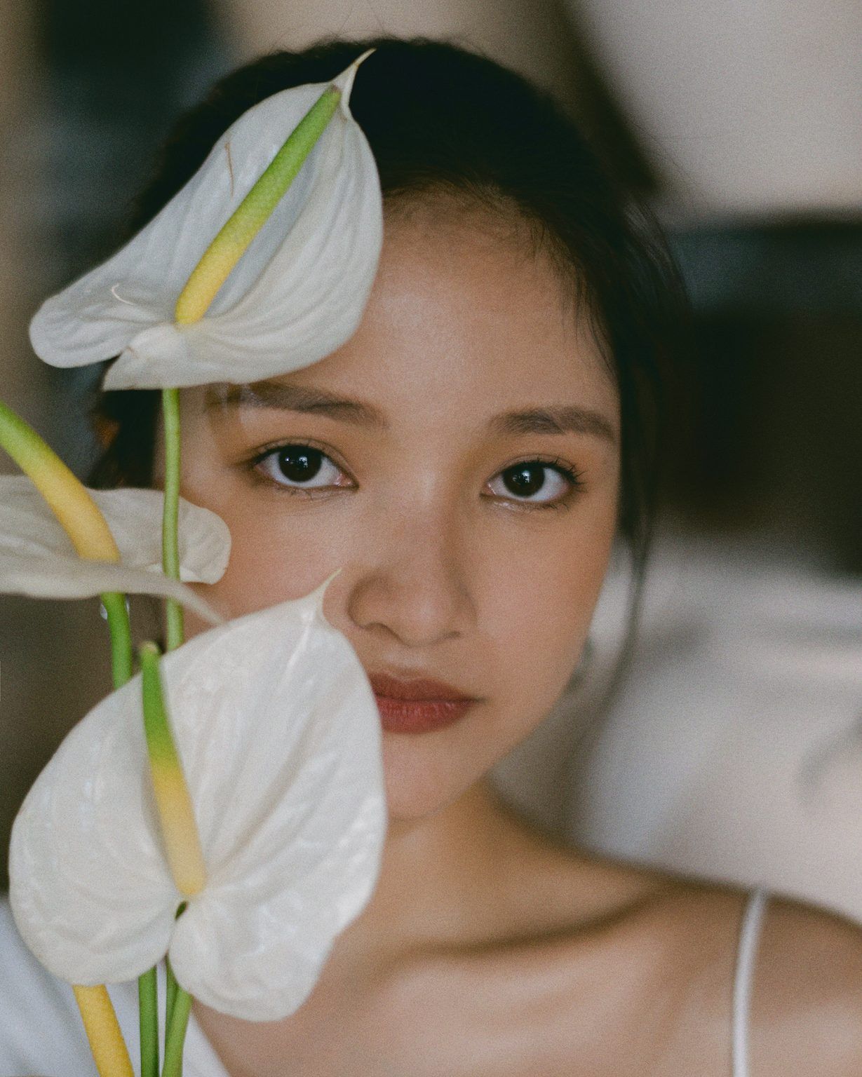 An artistic portrait featuring white anthurium flowers against a soft blurred background.