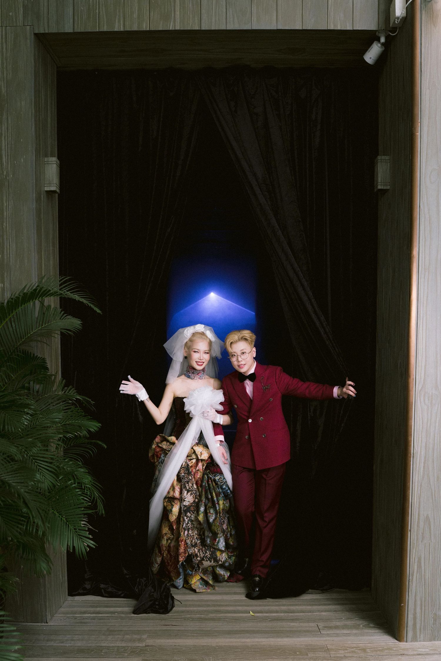 Two performers in contrasting burgundy and light outfits dance expressively on a dark stage with dramatic lighting.