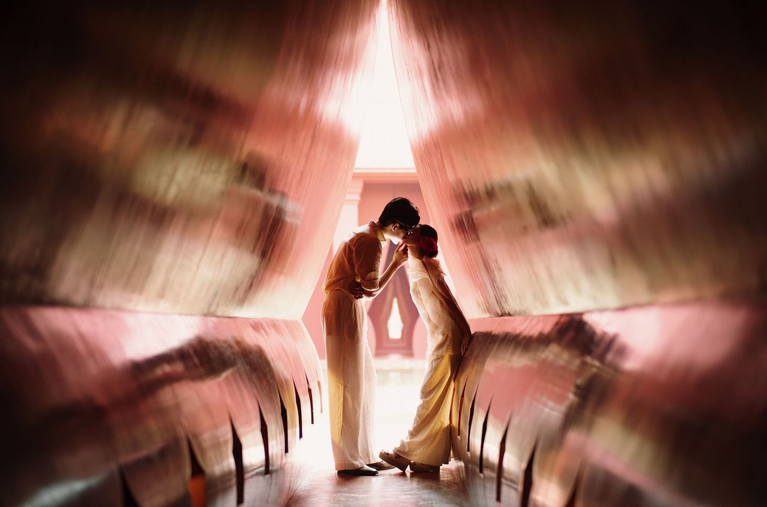 A dramatic wedding photo with silhouettes and light beams creating an artistic effect.